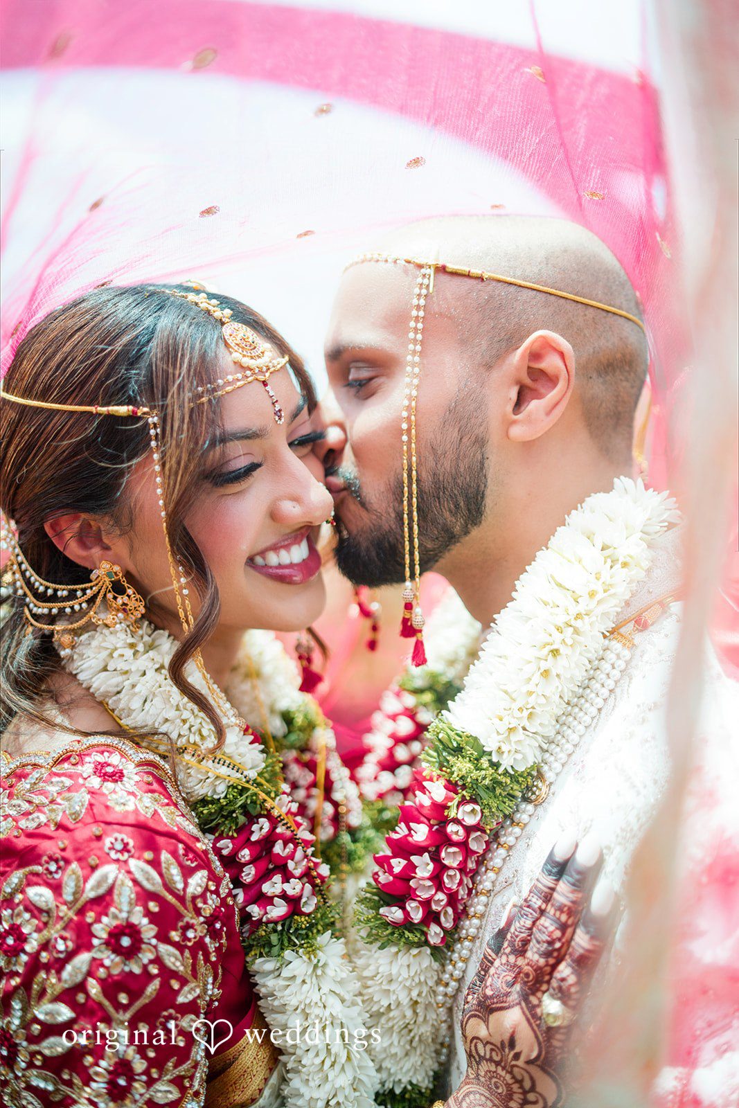 Close-up of a bride and groom sharing an affectionate moment while wearing wedding garlands.
