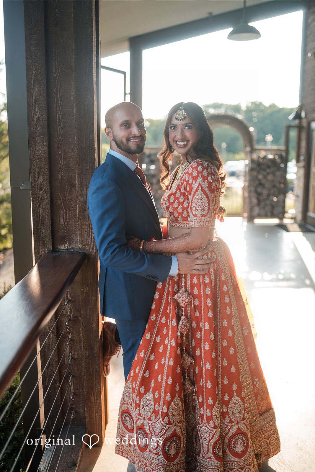 Groom in a blue suit holding the bride in an orange lehenga at Stone Crest.