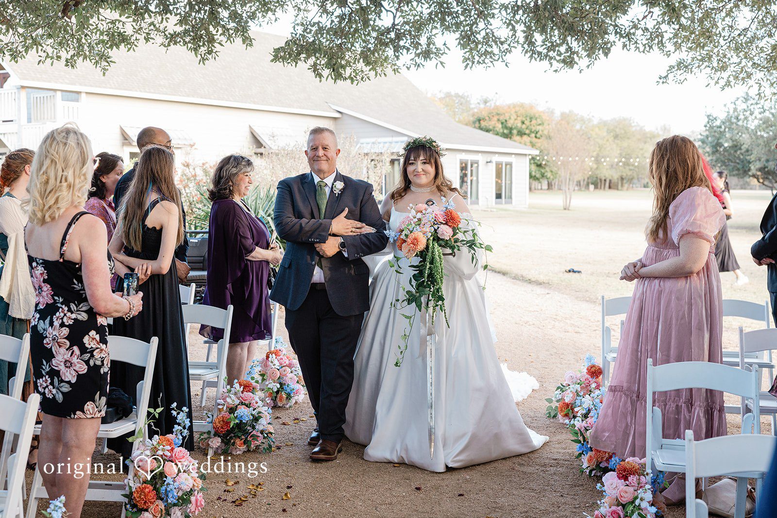 November 15, 2025 – Brittney & Benjamin- (ID-3986) A bride in a white gown walks down the aisle arm-in-arm with a man in a suit, surrounded by wedding guests