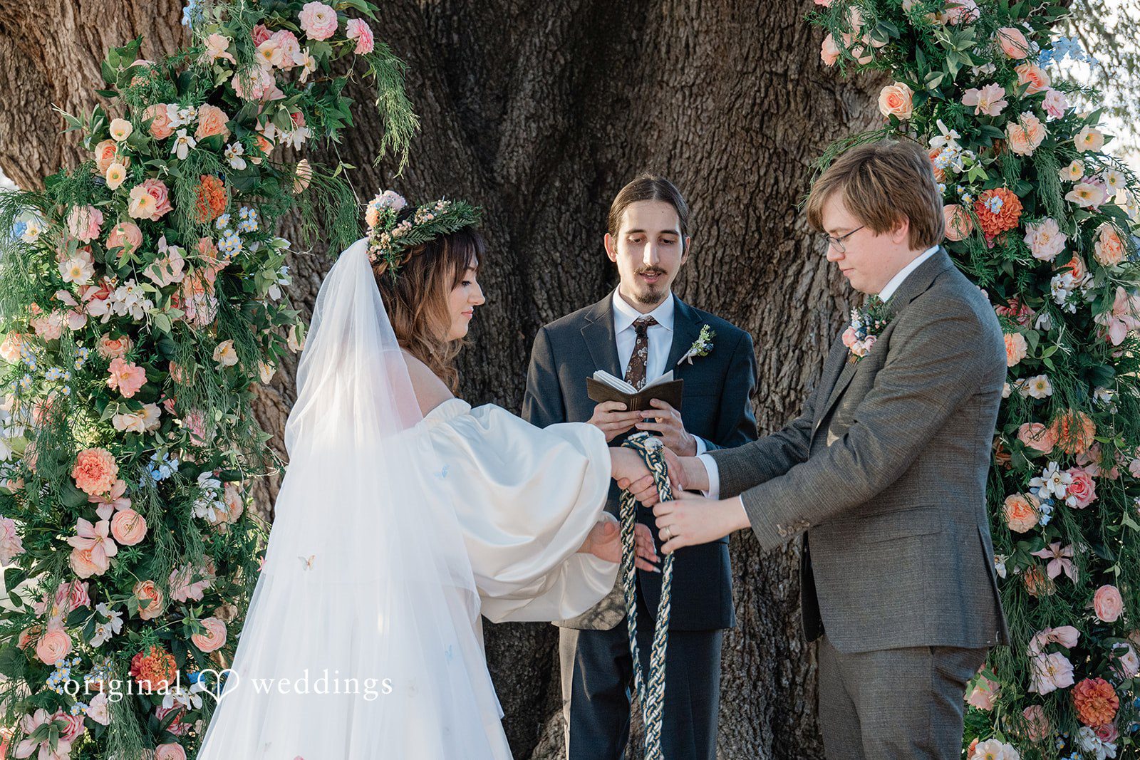 Brittney + Benjamin A bride and groom holding hands during their ceremony in front of an officiant.