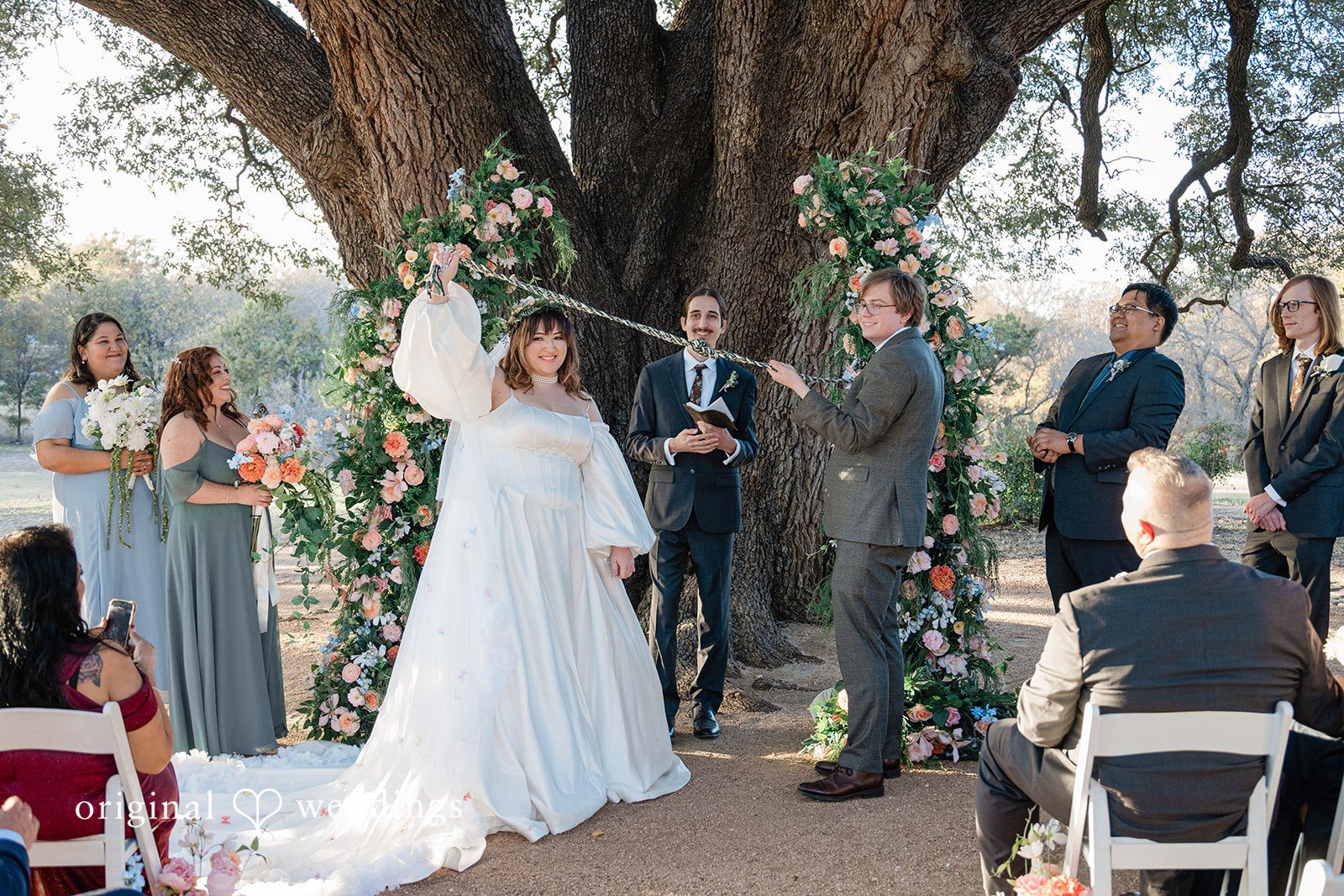 Brittney + Benjamin A bride and groom standing together at the altar surrounded by their wedding party.