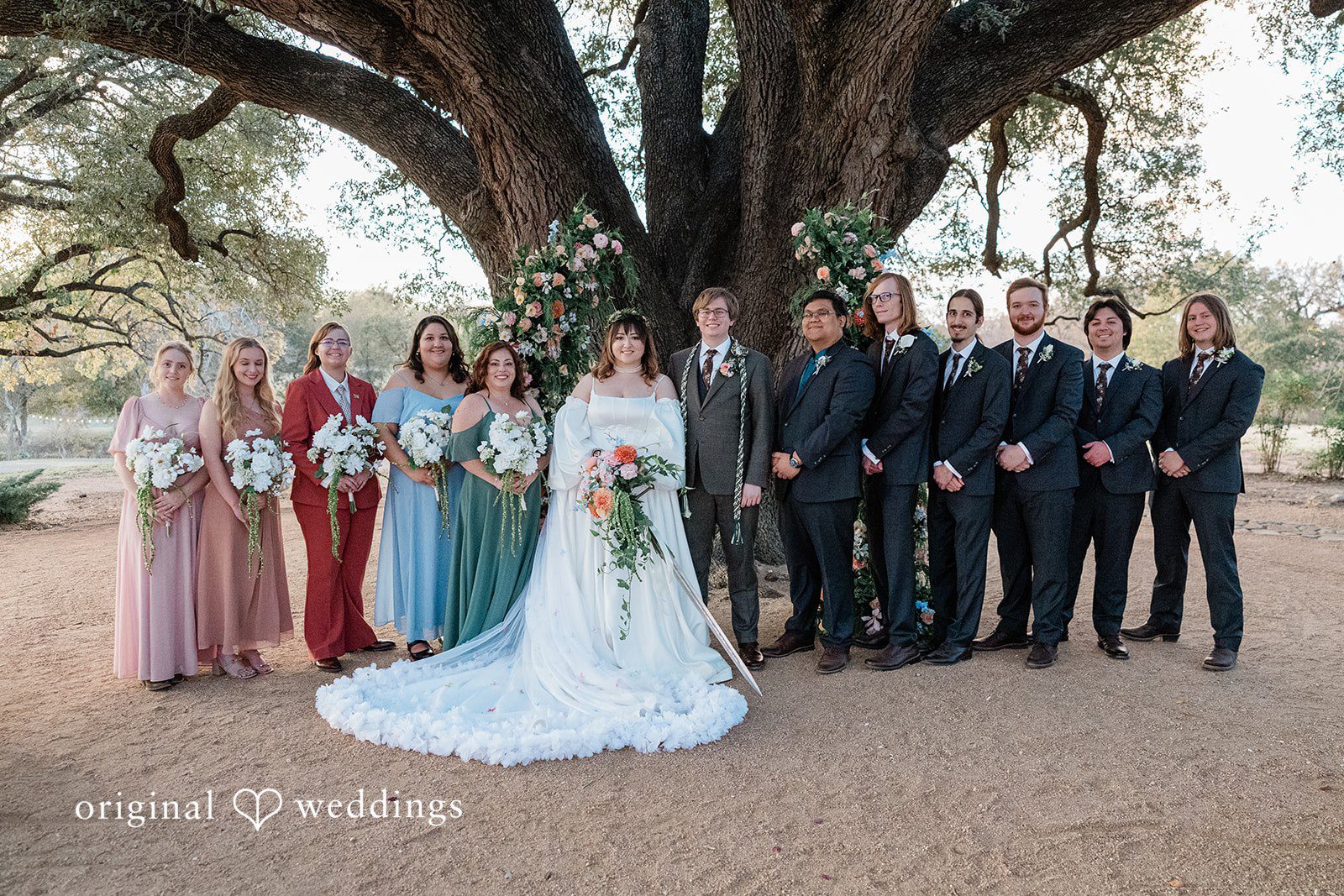Brittney + Benjamin A wedding party posing together in front of a large tree.