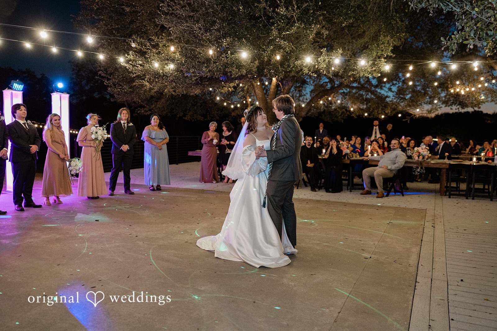 Brittney + Benjamin A bride and groom sharing their first dance on a lit dance floor.