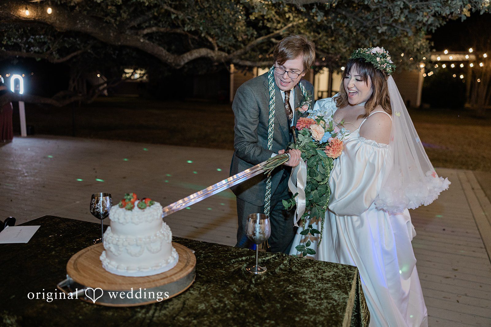 Brittney + Benjamin A bride and groom cutting their tiered wedding cake at night.