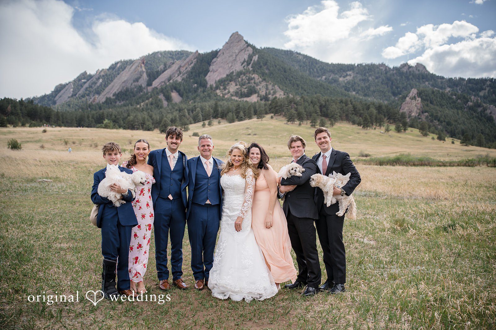Jacquelyn + Millard Family portrait with loved ones and dogs against the Flatirons backdrop at Sunrise Amphitheater.