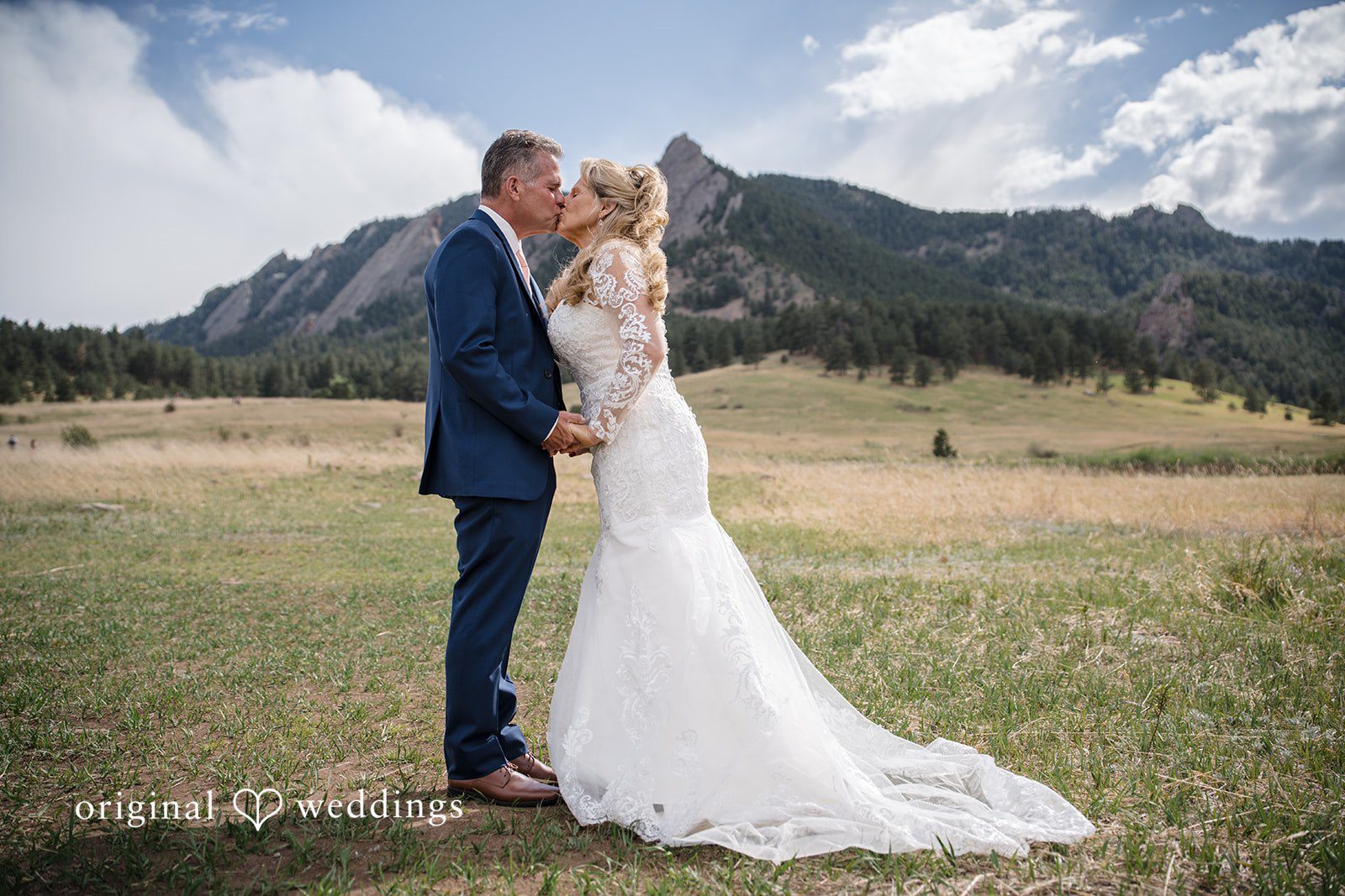 Jacquelyn + Millard Bride and groom sharing a kiss with the Flatirons in the background