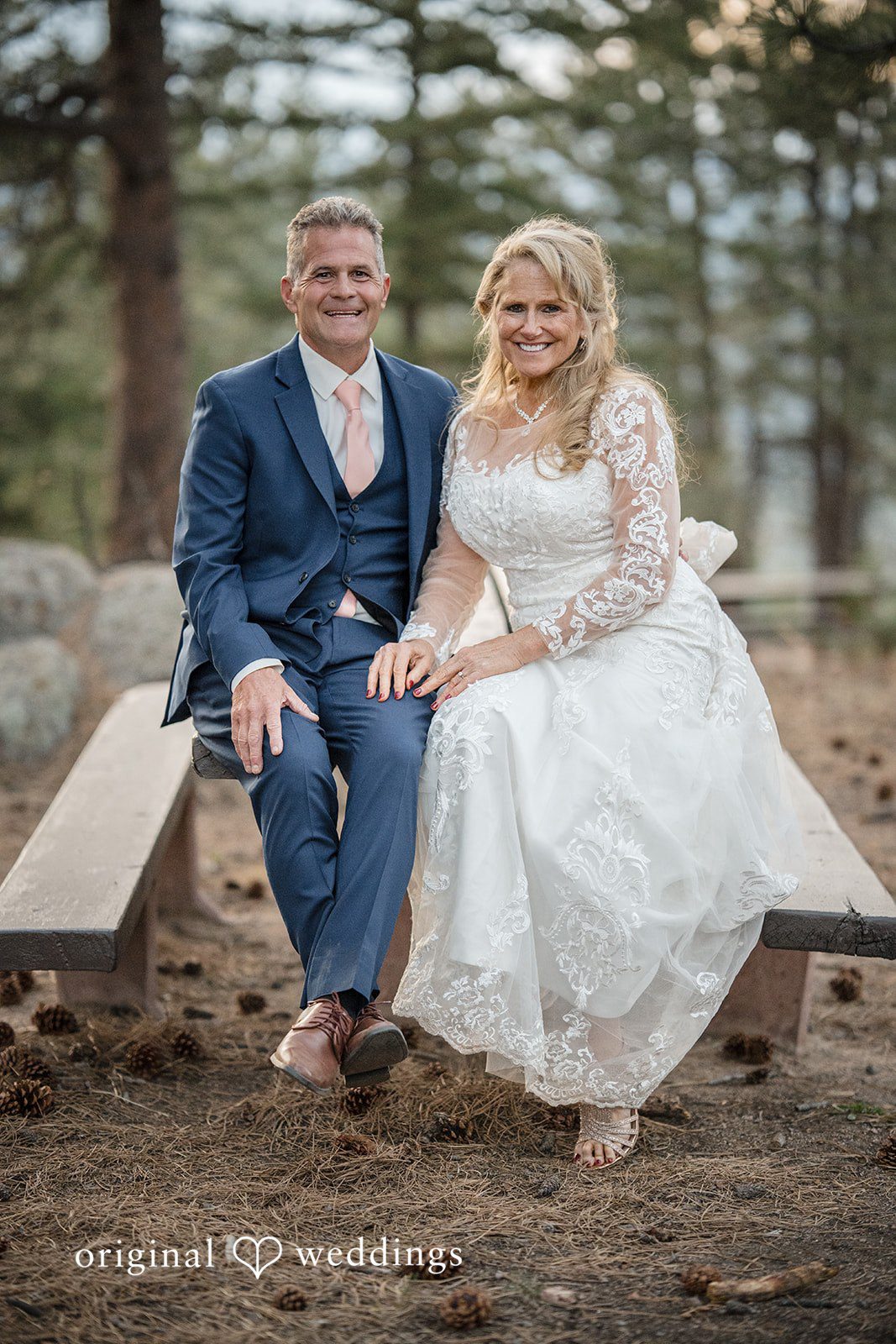 Jacquelyn + Millard Bride and groom seated together for a portrait among the pine trees at Sunrise Amphitheater.