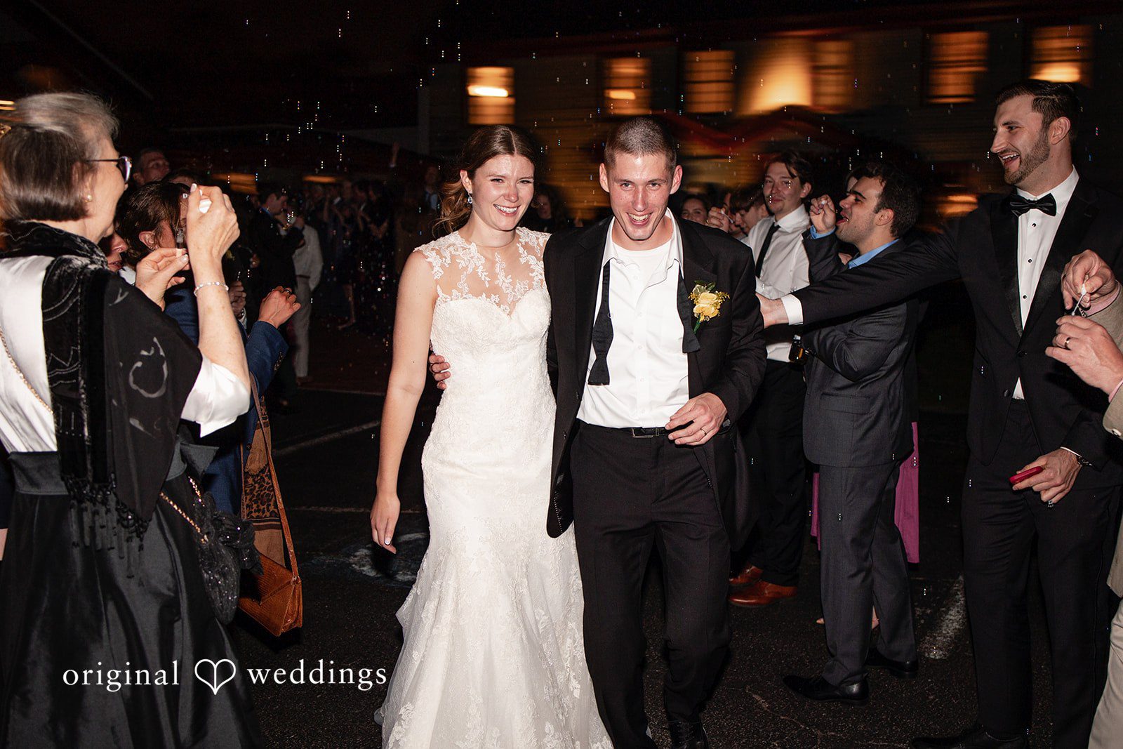 Alanna + Stan Newlyweds smile while leaving reception surrounded by loved ones.