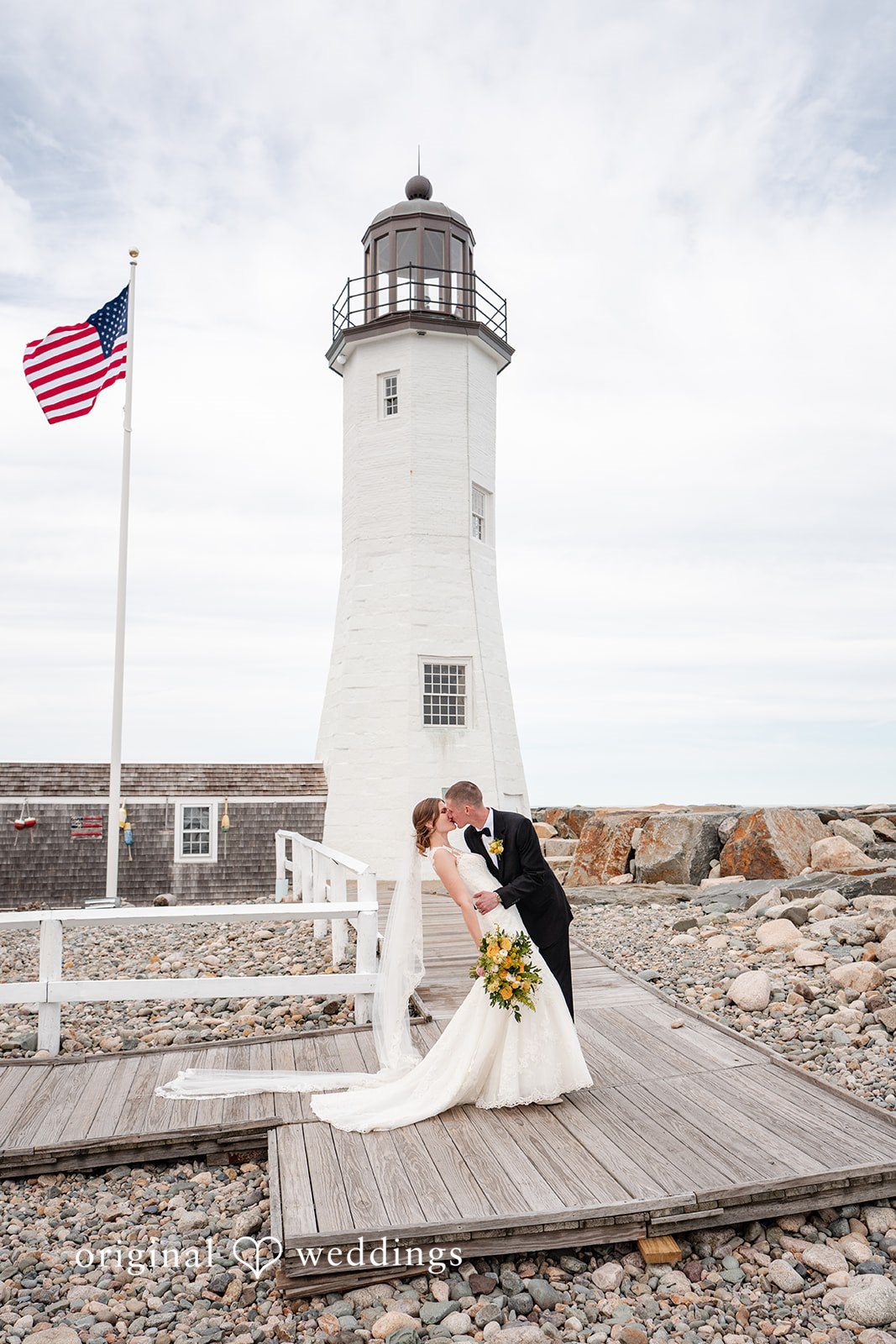 Alanna + Stan Romantic wedding portrait of bride and groom kissing near a seaside lighthouse.