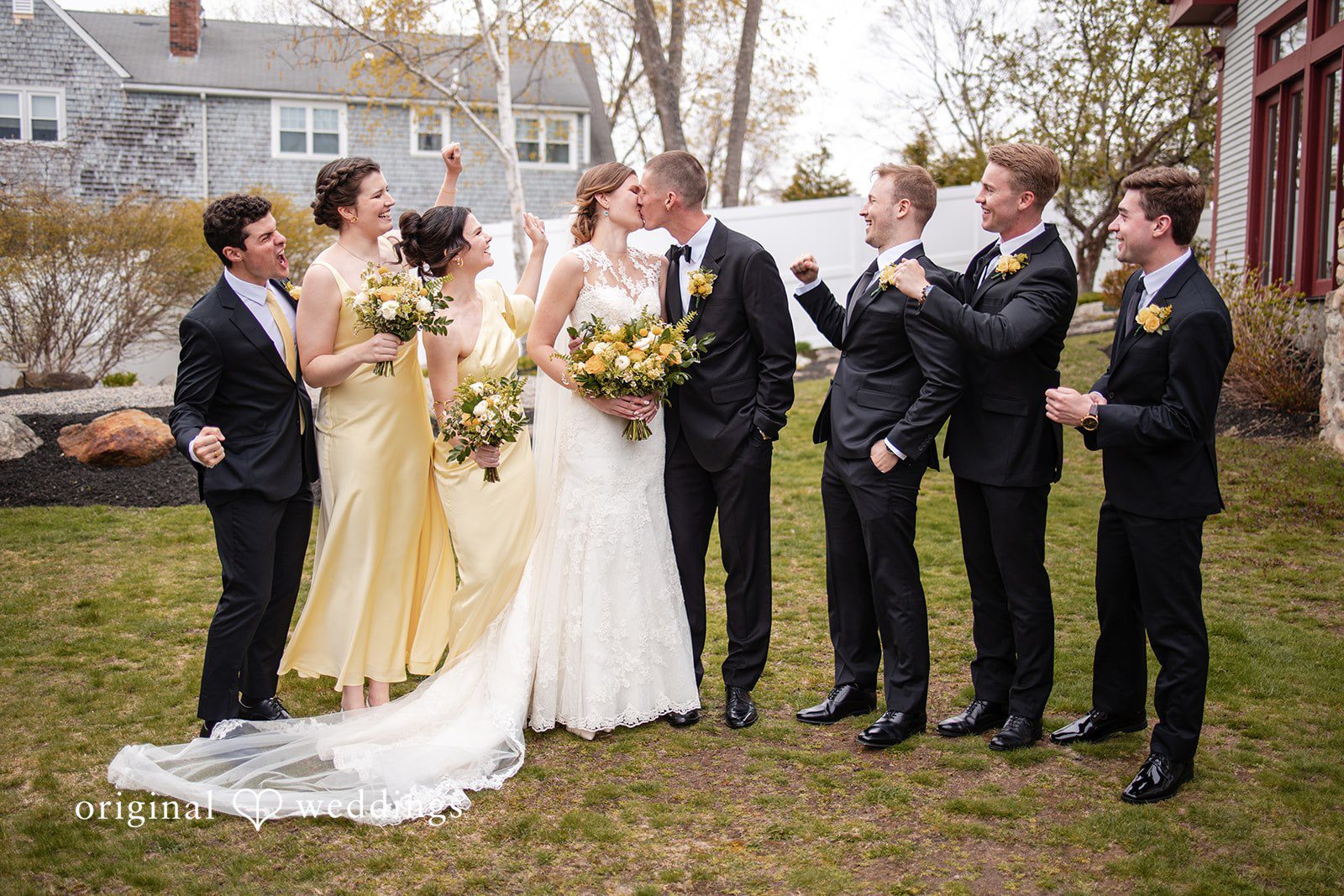 Alanna + Stan Newlyweds share a kiss during group wedding photo.