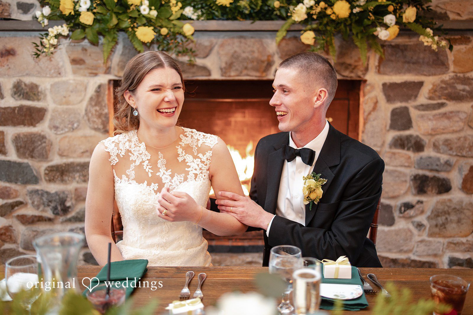 Alanna + Stan Bride and groom enjoy a cheerful moment at decorated reception table.