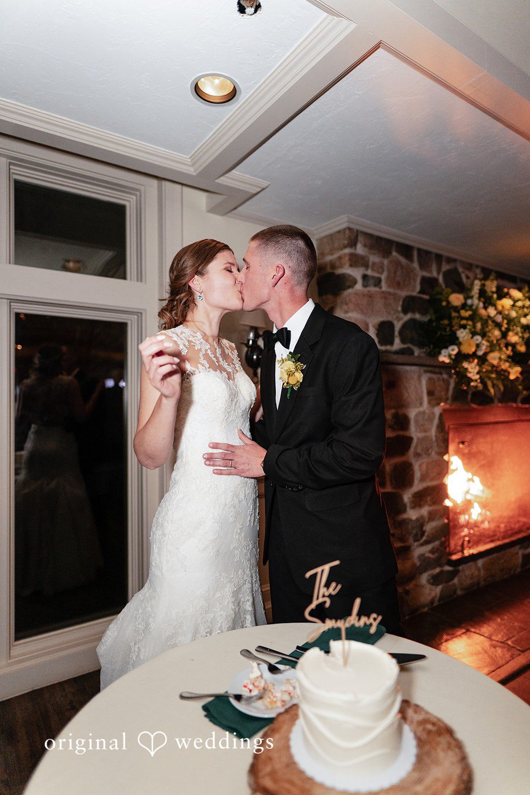 Alanna + Stan Bride and groom share a kiss beside wedding cake during reception.