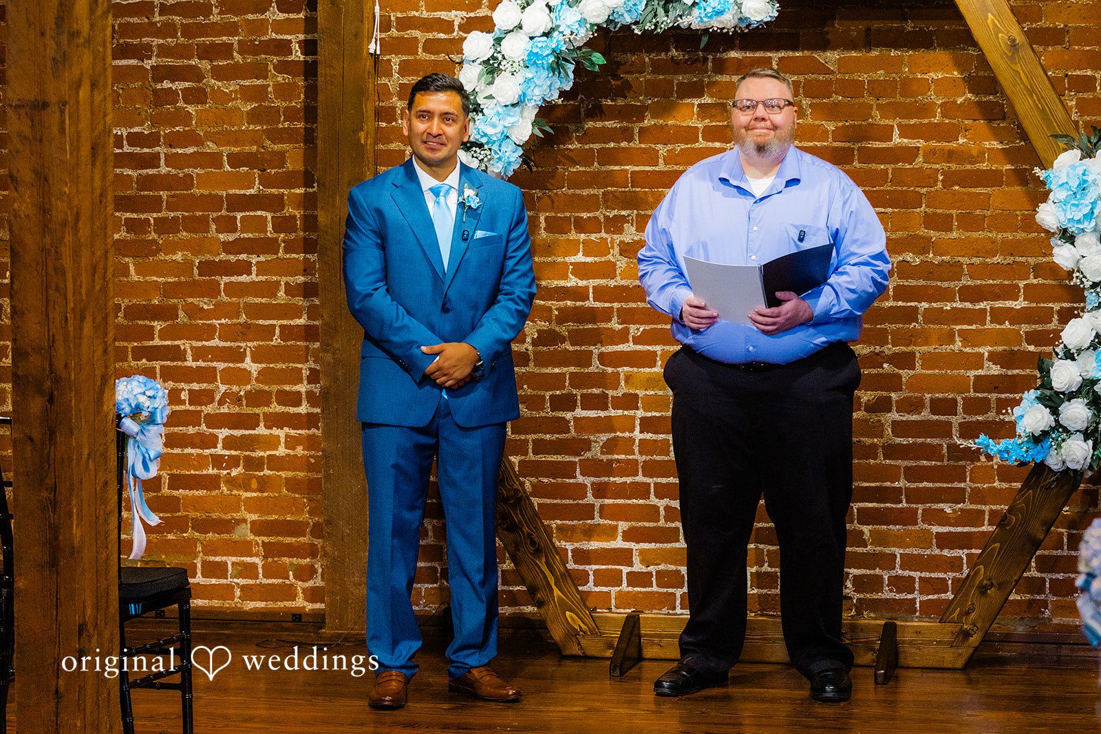 A groom in a blue suit and an officiant standing at the altar.