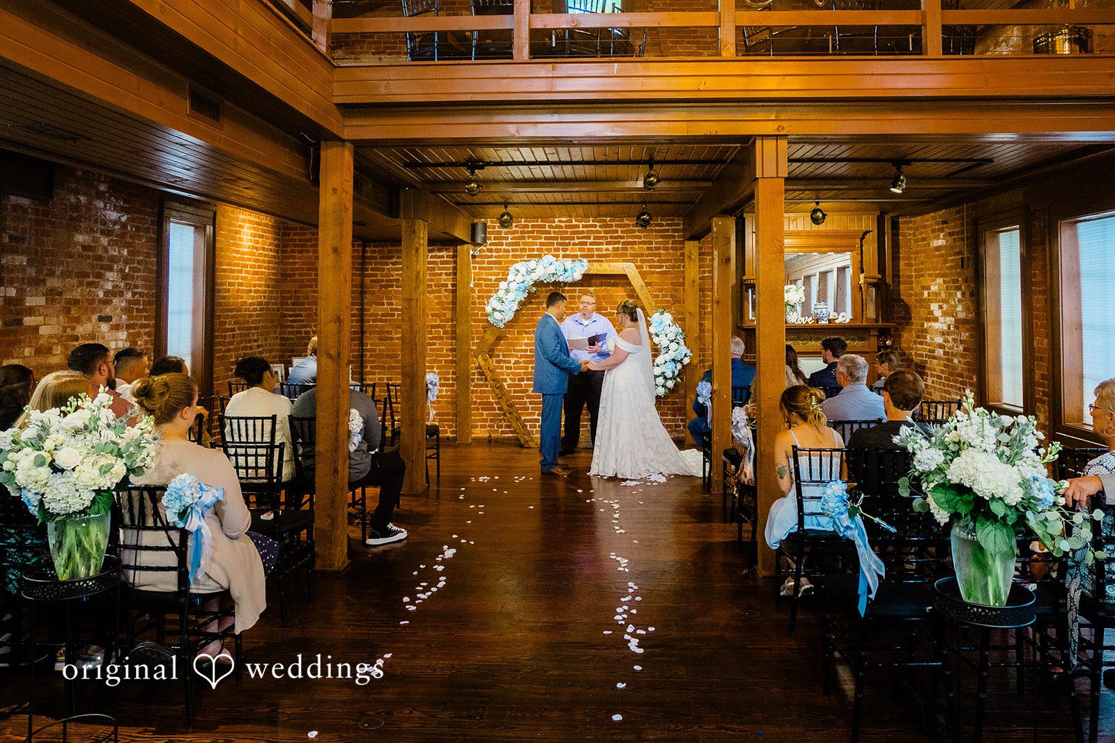 A wide view of a wedding ceremony down the aisle with guests seated on both sides.