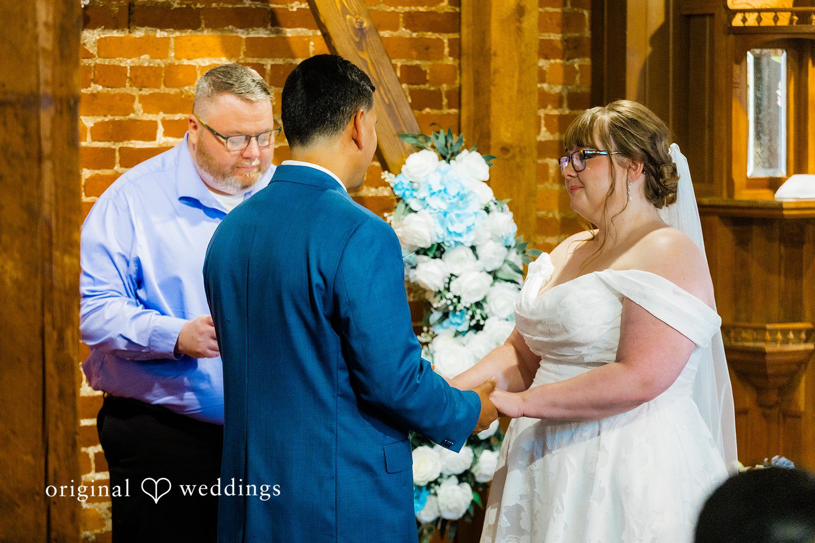 A close-up of a bride and groom facing each other at the altar with the officiant.