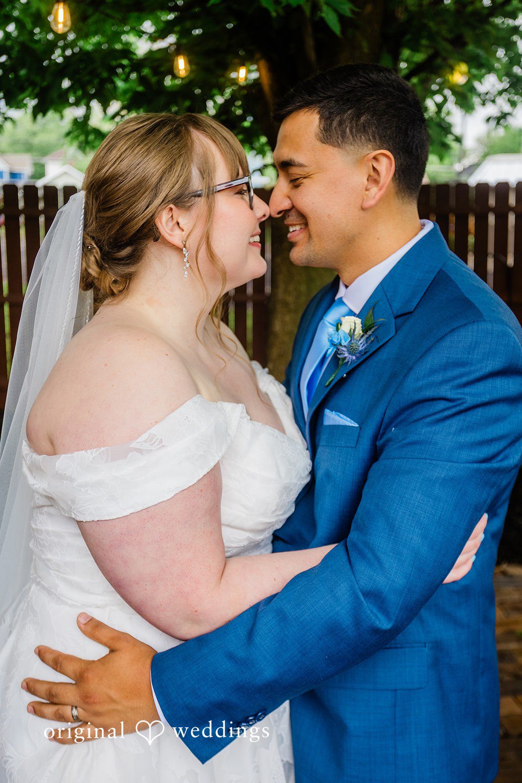 A close-up of a bride and groom embracing and smiling at each other.