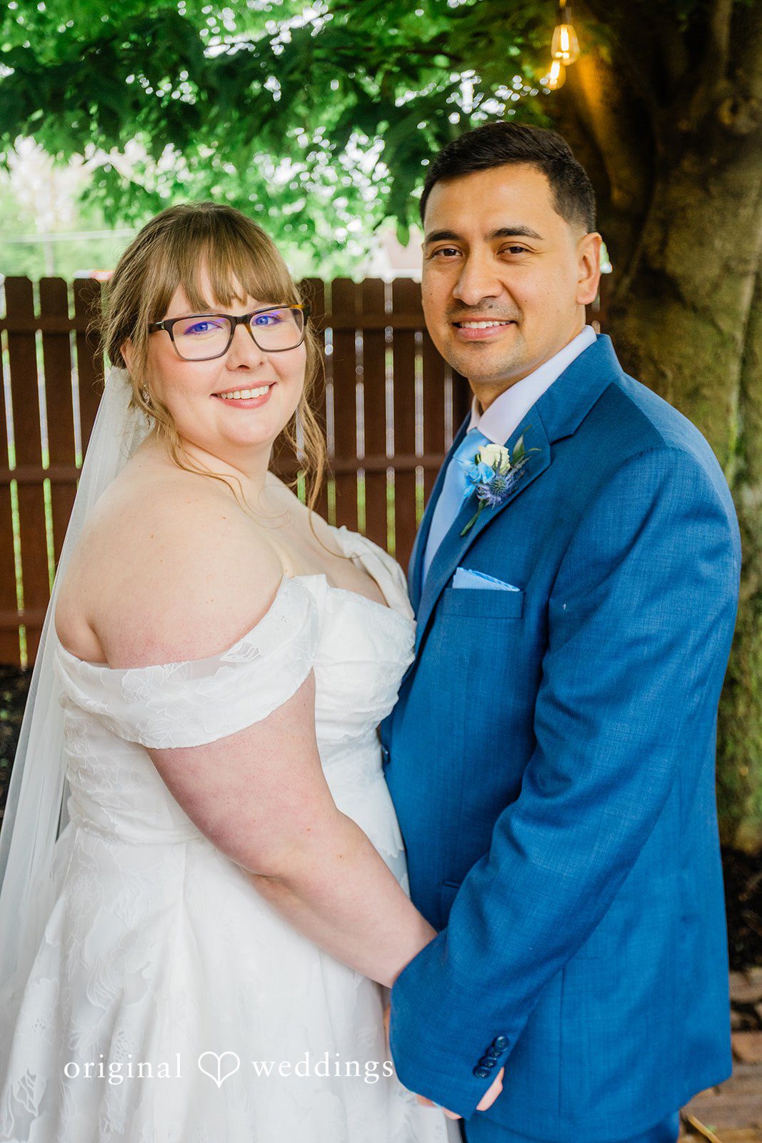 A smiling bride and groom embracing while posing together at The Barrel House.