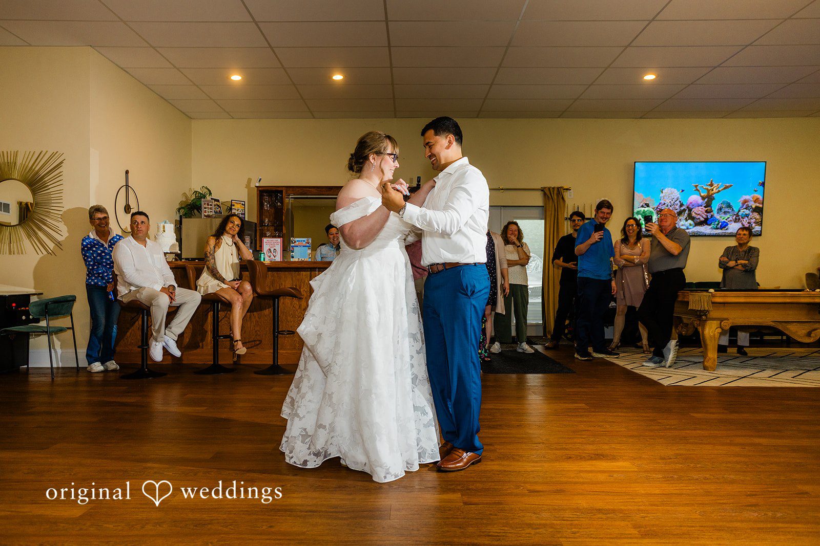 A bride and groom dancing together on a wooden dance floor during their reception.
