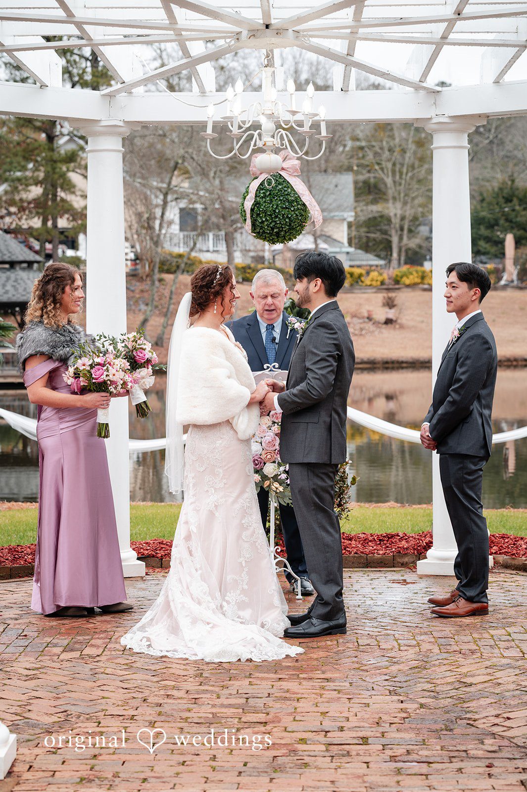Emsley + Sean Atlanta Wedding Photographers capturing couple holding hands before priest while looking at each other at The Farley Estate by Original Weddings