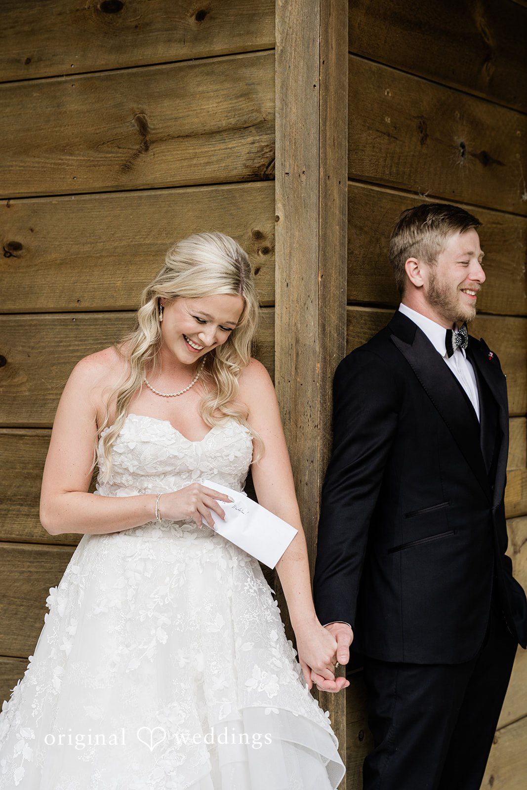 Madeline + John Bride and groom holding hands beside a lakeside cabin