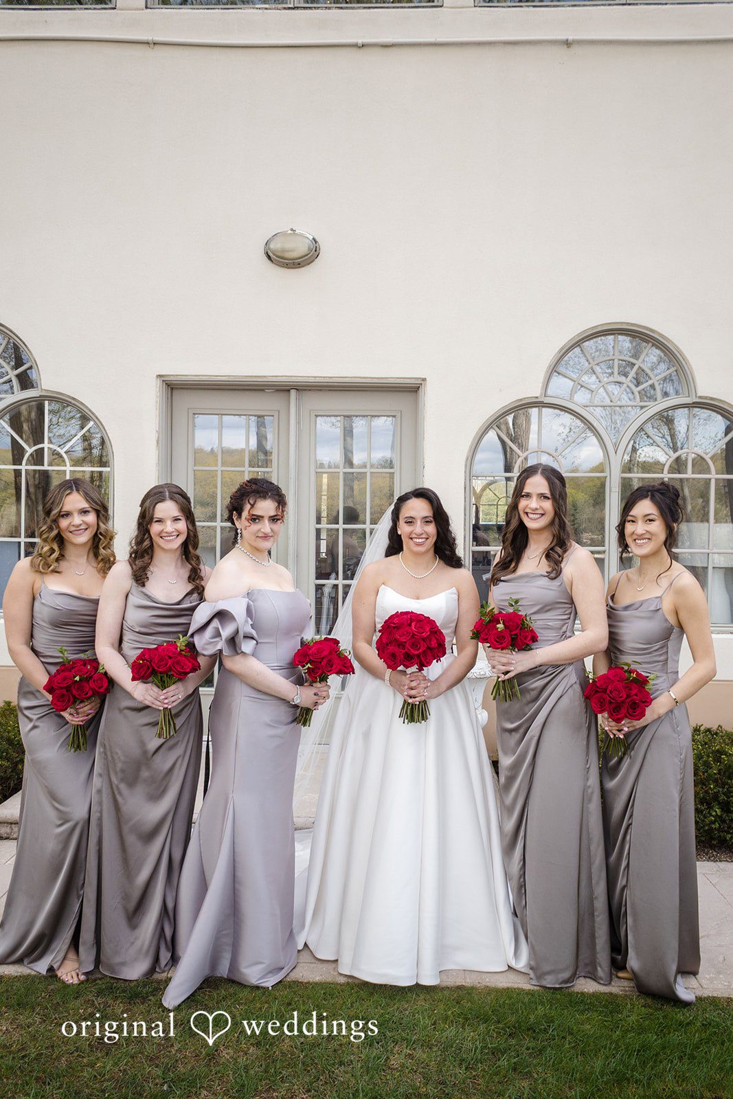 Bride and bridesmaids portrait with red rose bouquets at The Waterview