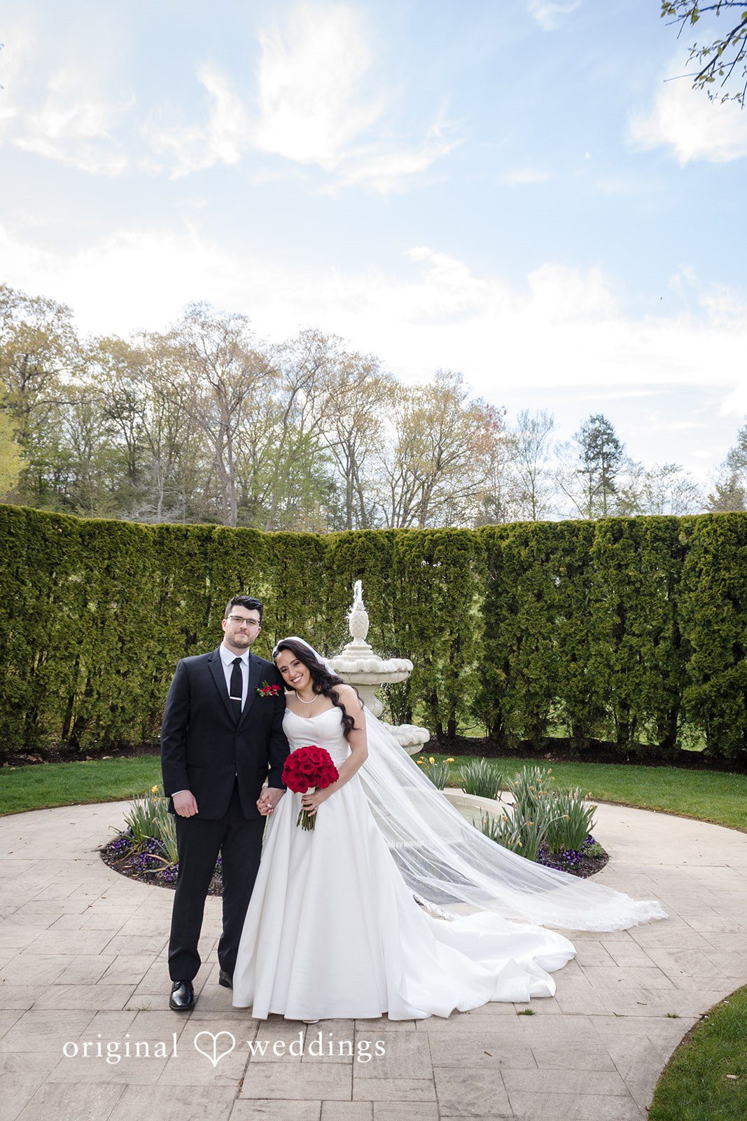 Bride and groom posing in front of fountain garden