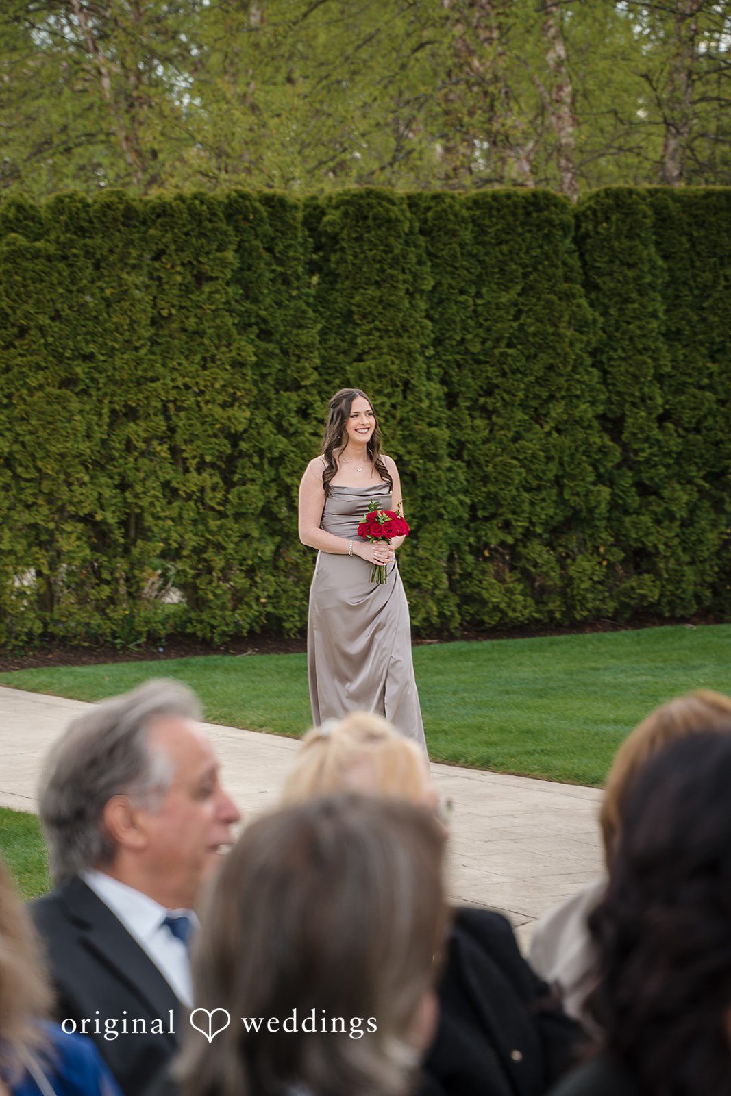 Bridesmaid walking down aisle with red bouquet at The Waterview