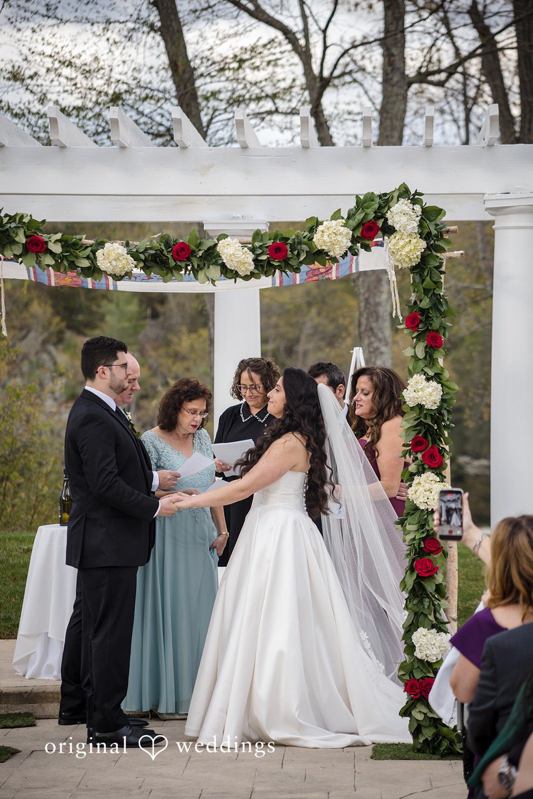 Close-up of bride and groom holding hands during heartfelt wedding vows.