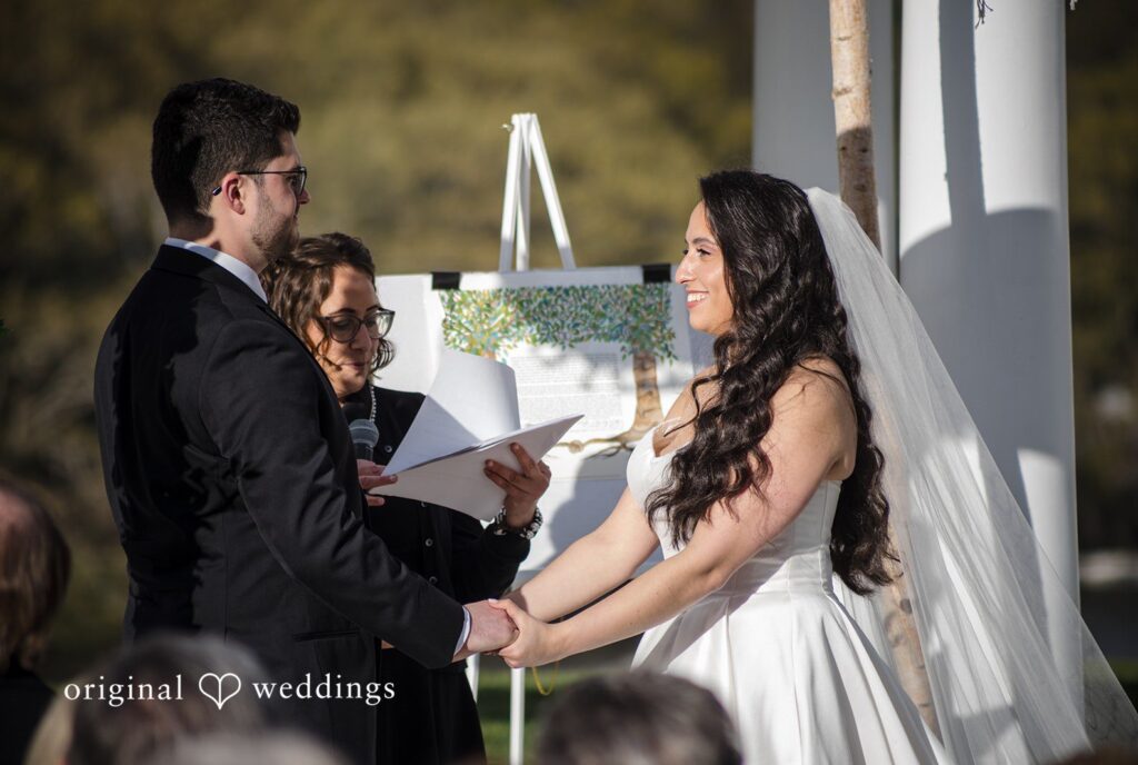 Close-up of bride and groom holding hands during heartfelt wedding vows.