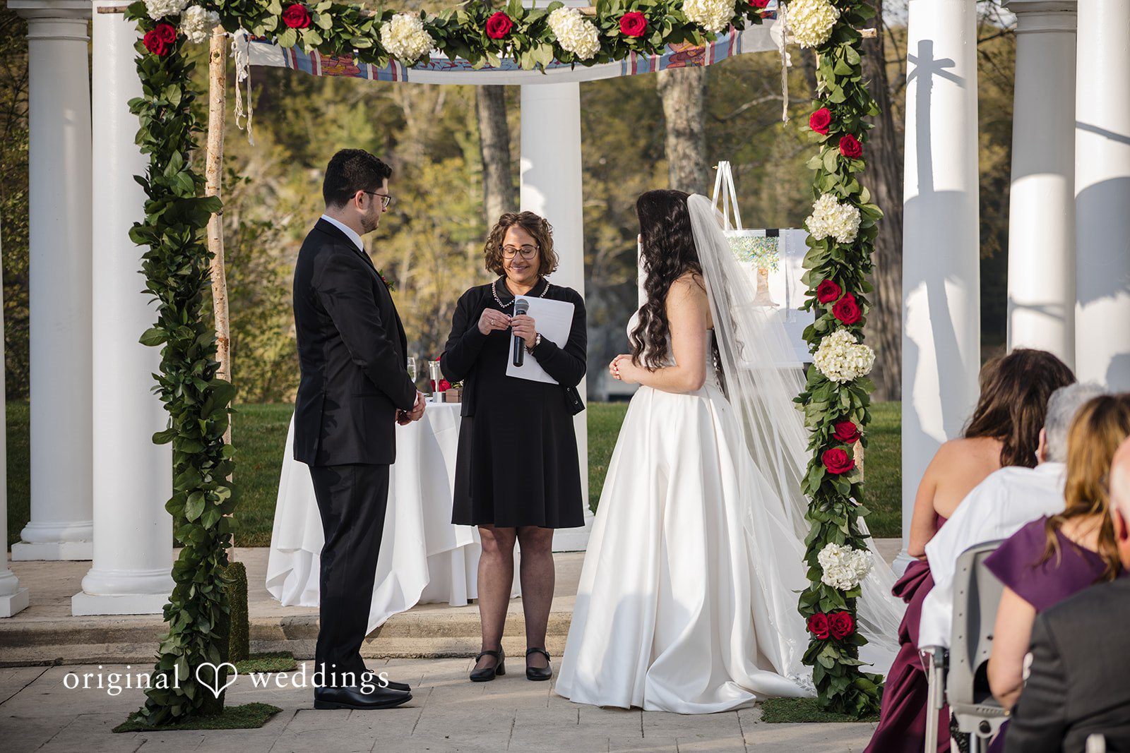 Romantic wedding moment under greenery and rose-covered canopy.