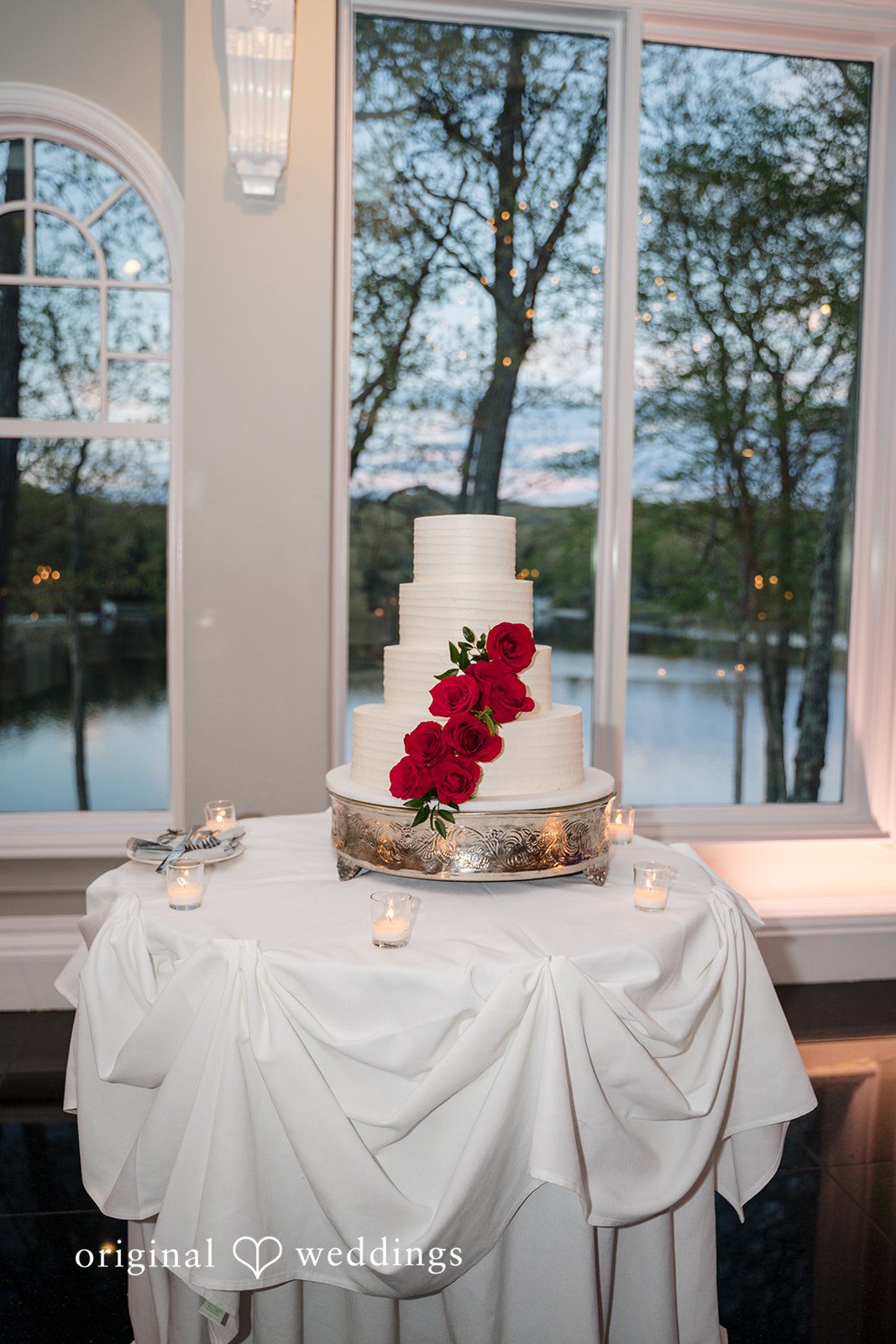 Three-tier wedding cake with red rose floral accents at The Waterview