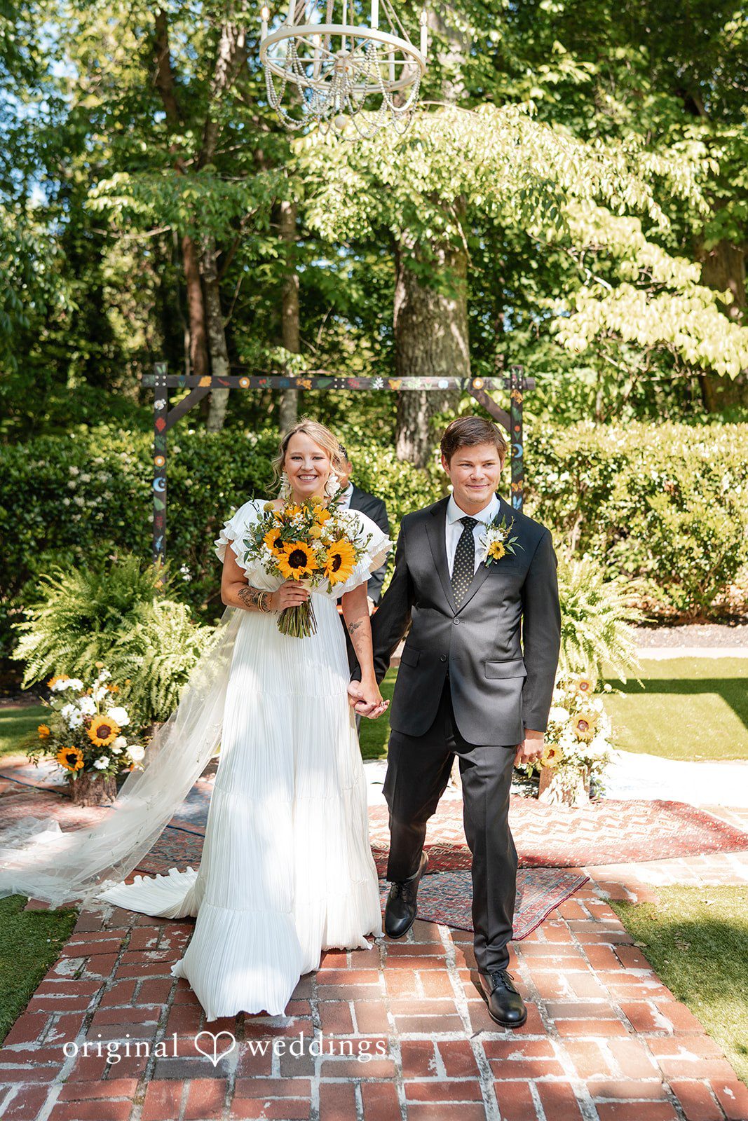 Elizabeth + Zodi Bride and groom walking together across a green lawn