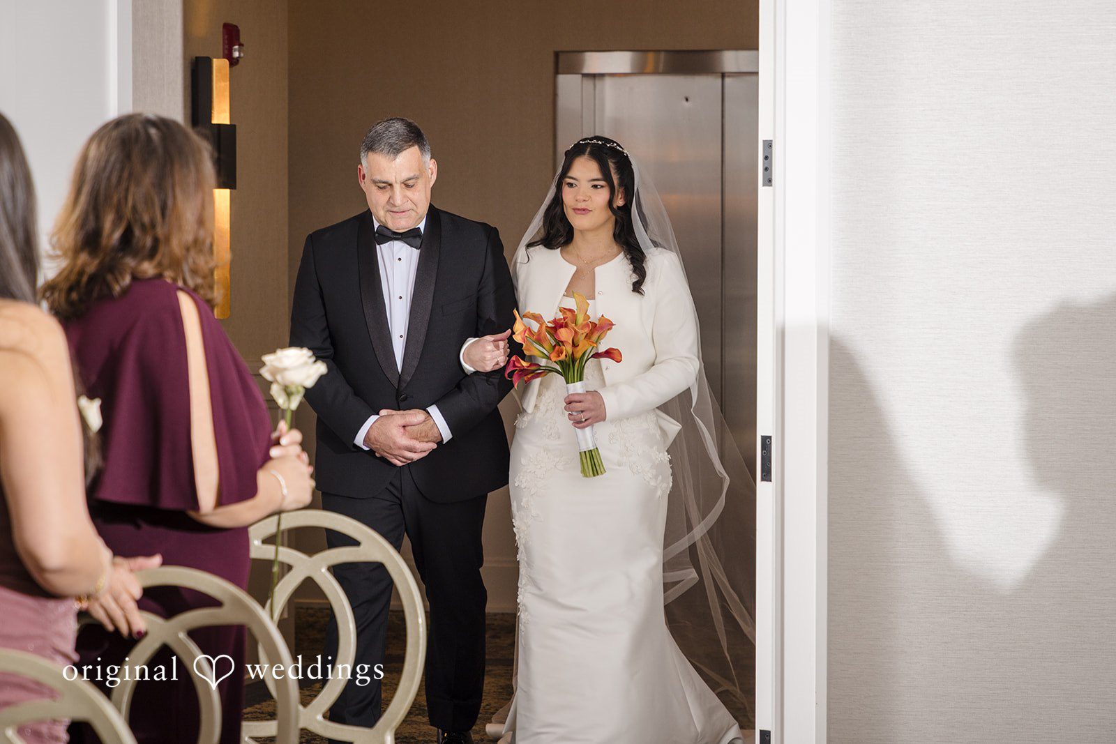 Maria + Eddy A bride walks down the wedding aisle escorted by a man in a tuxedo.