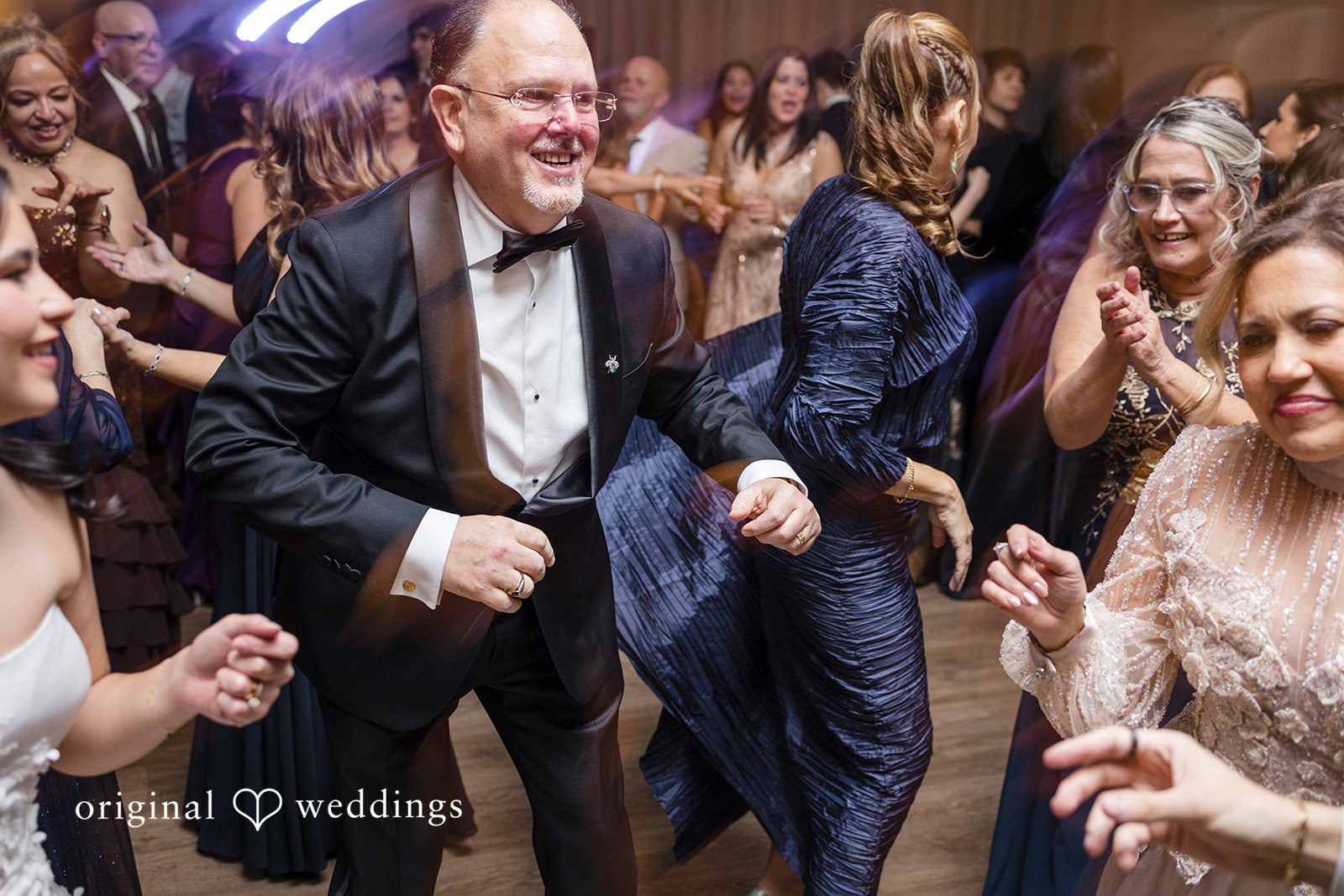 Maria + Eddy Wedding guests dance and celebrate together on a crowded dance floor.