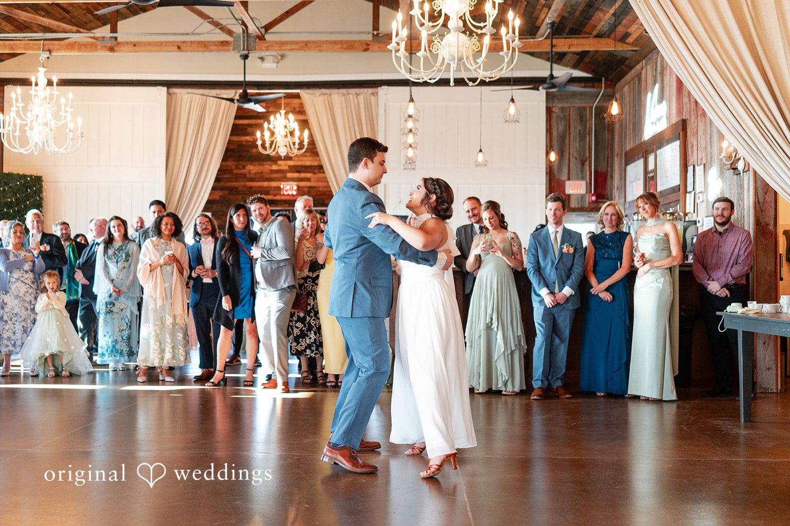 Bride and groom sharing their first dance surrounded by wedding guests.