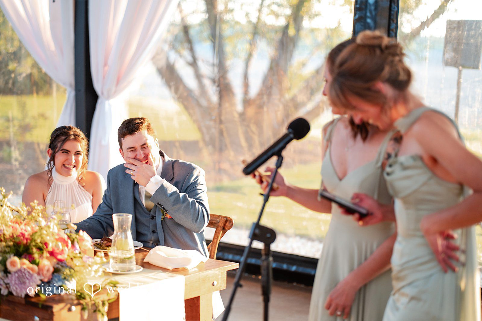 Bride and groom laughing during a heartfelt wedding reception toast.