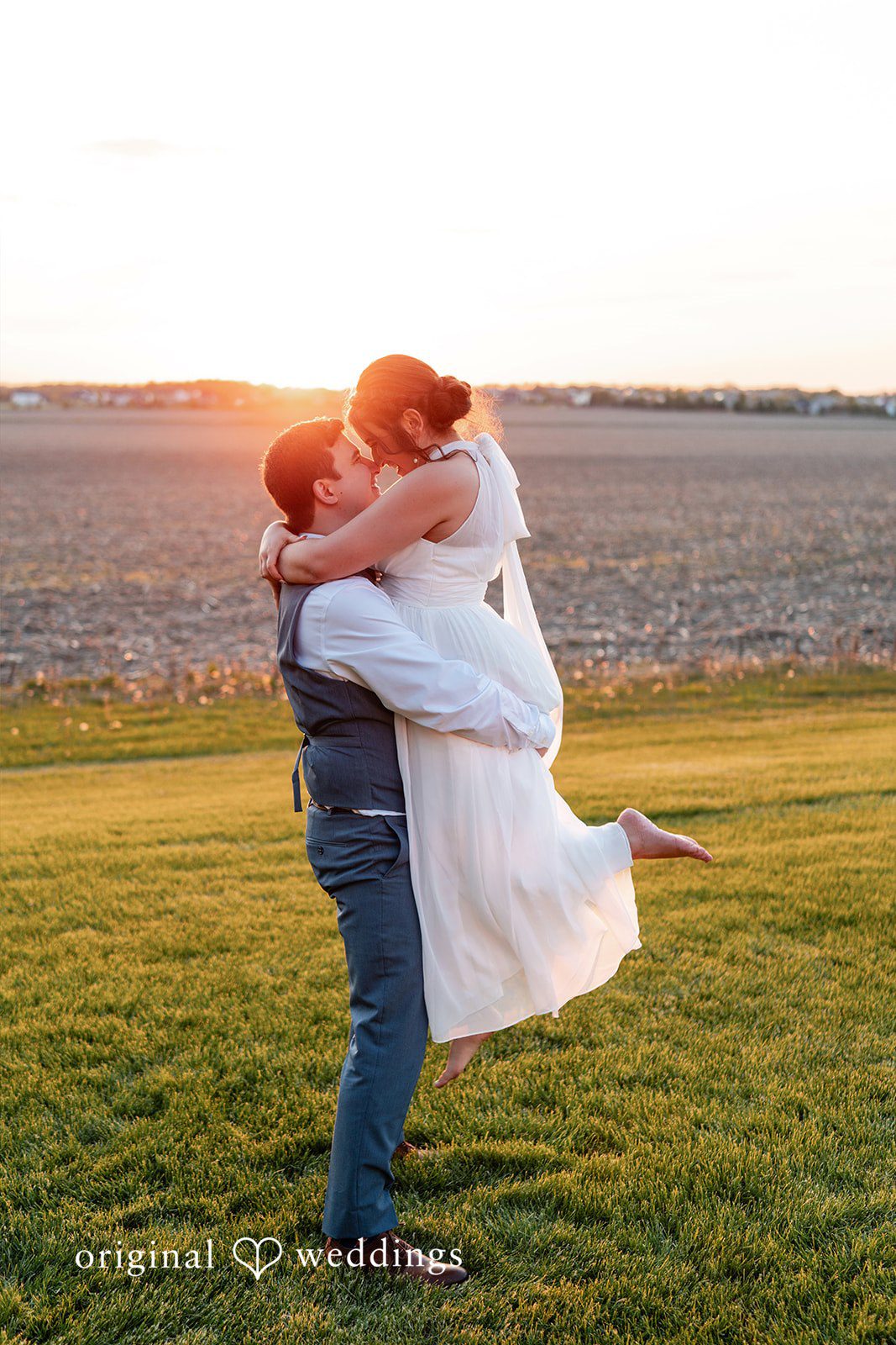 Bride and groom sharing a sunset kiss on the lawn.