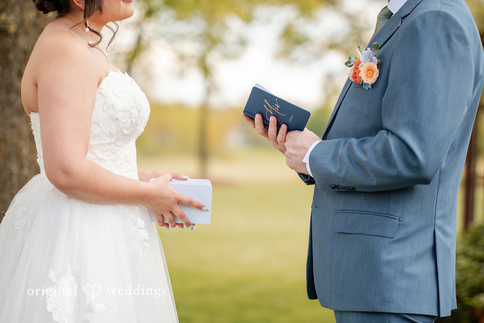 Bride and groom exchanging handwritten vows during their outdoor wedding ceremony.