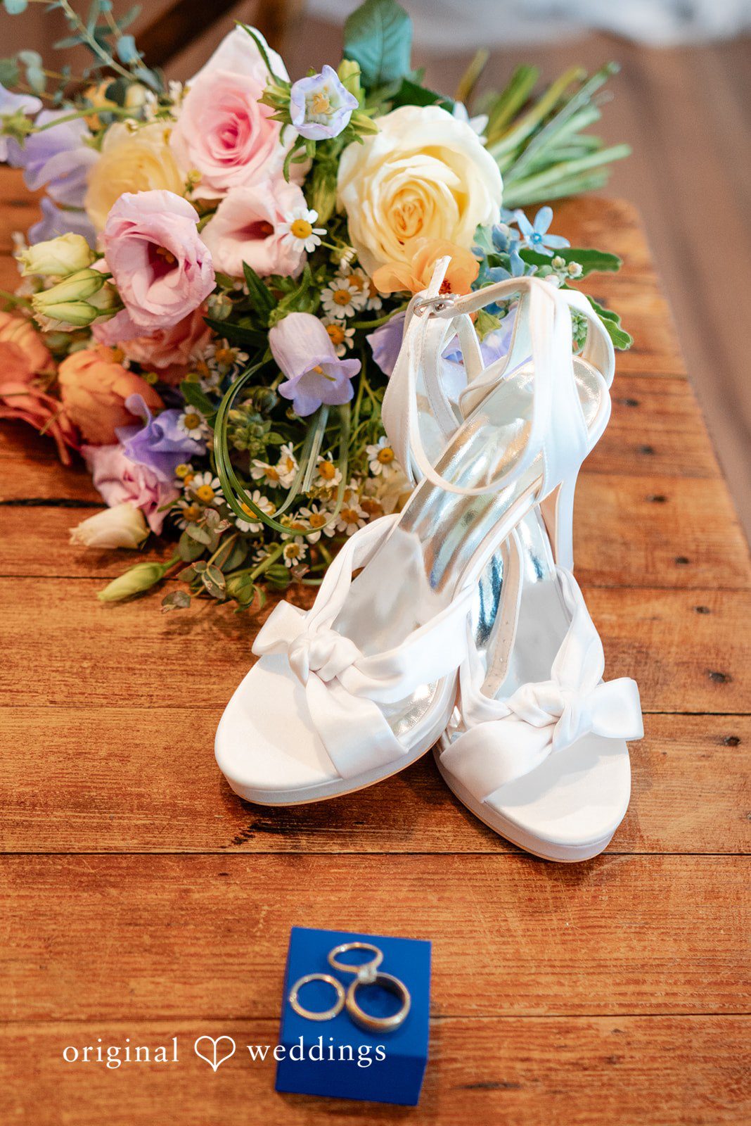 Detailed picture of bridal shoes and accessories placed with flowers.