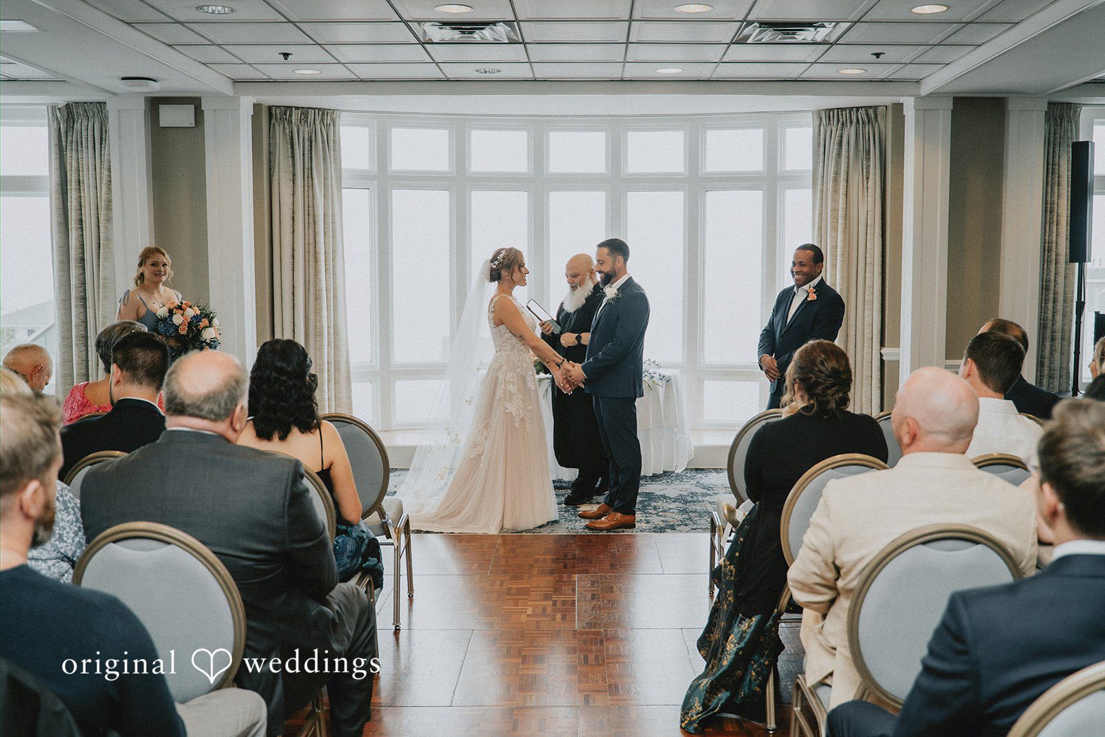 Taylor + David Bride and groom holding hands during the ceremony in a wide-angle view