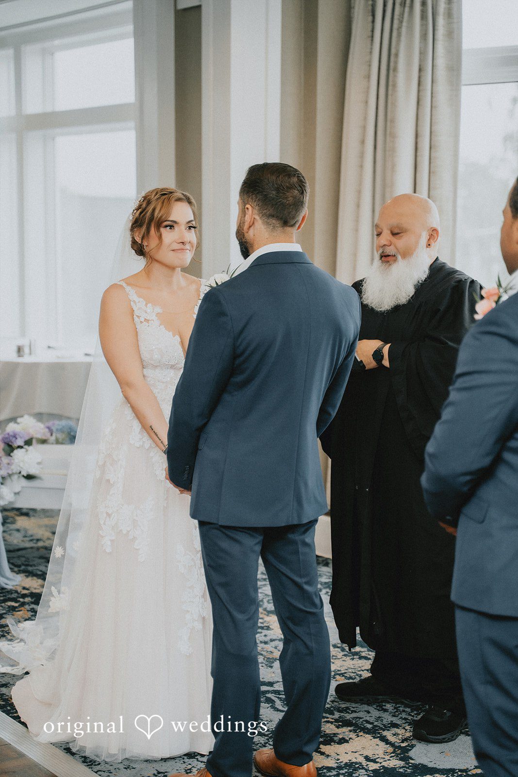 Taylor + David Groom viewed from behind while looking at the bride during the ceremony