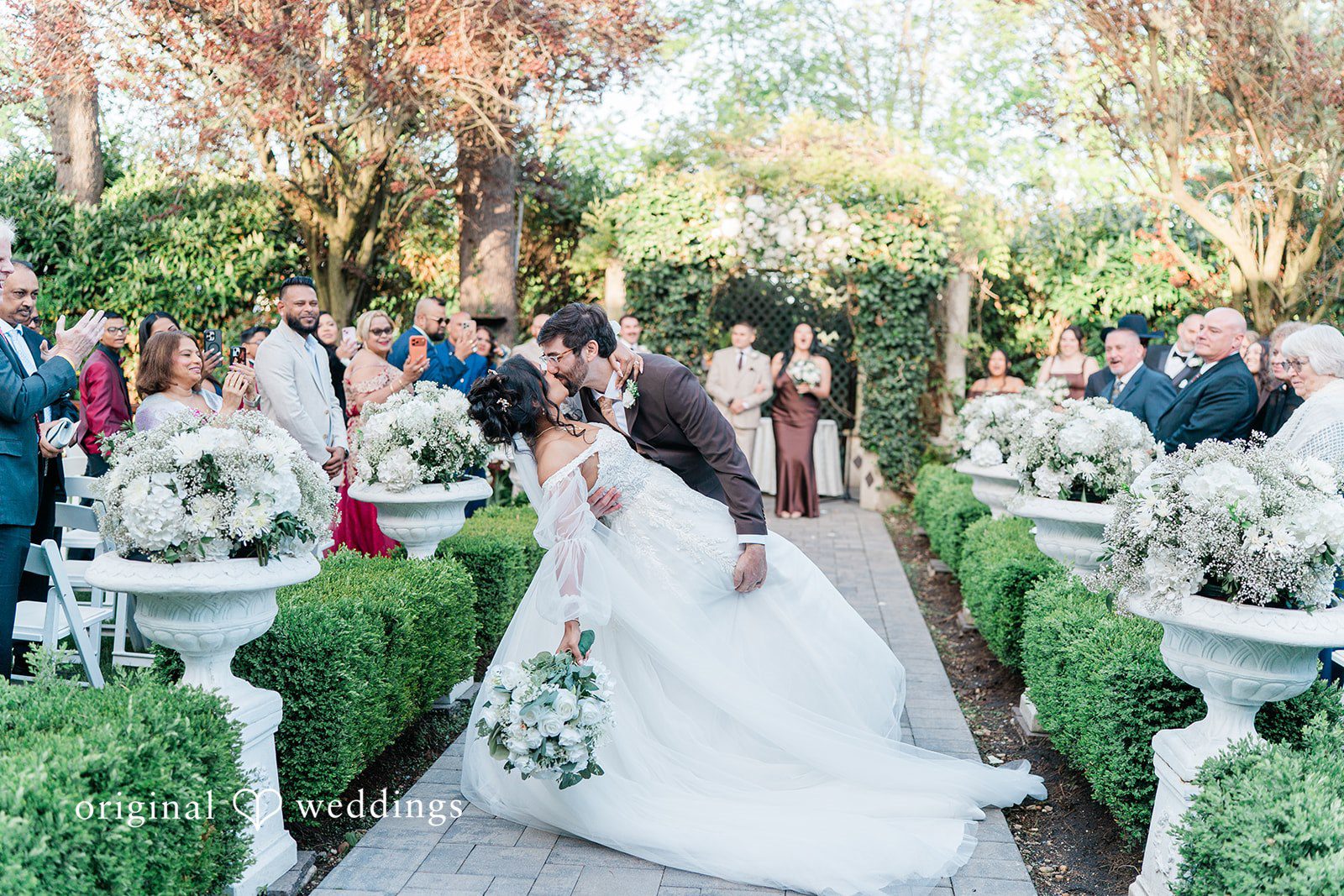 Sabrina + Jonathan Bride and groom sharing a kiss walking through the guests