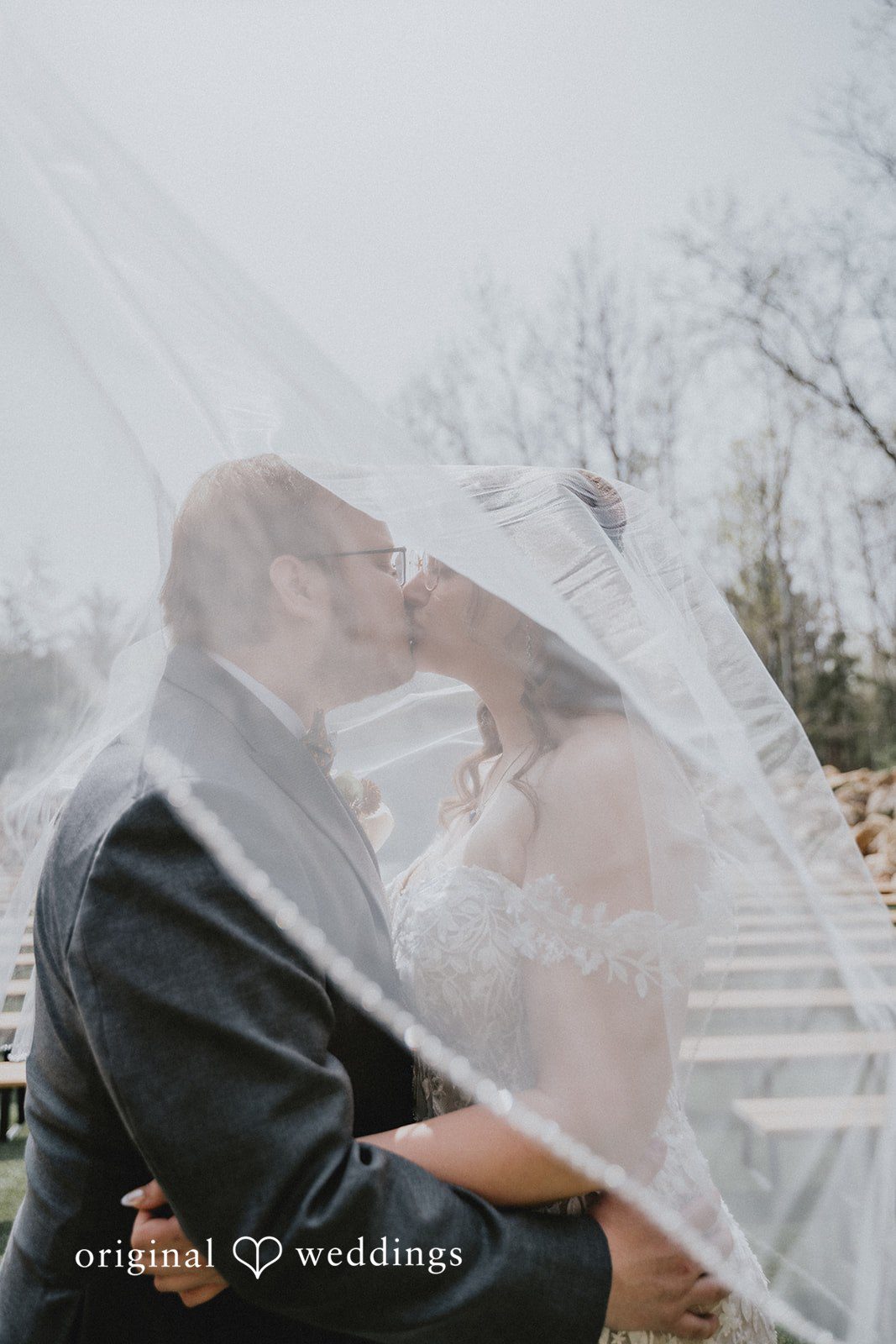 Ashlee + Colby Bride and groom sharing a kiss beneath the veil in a romantic wedding portrait