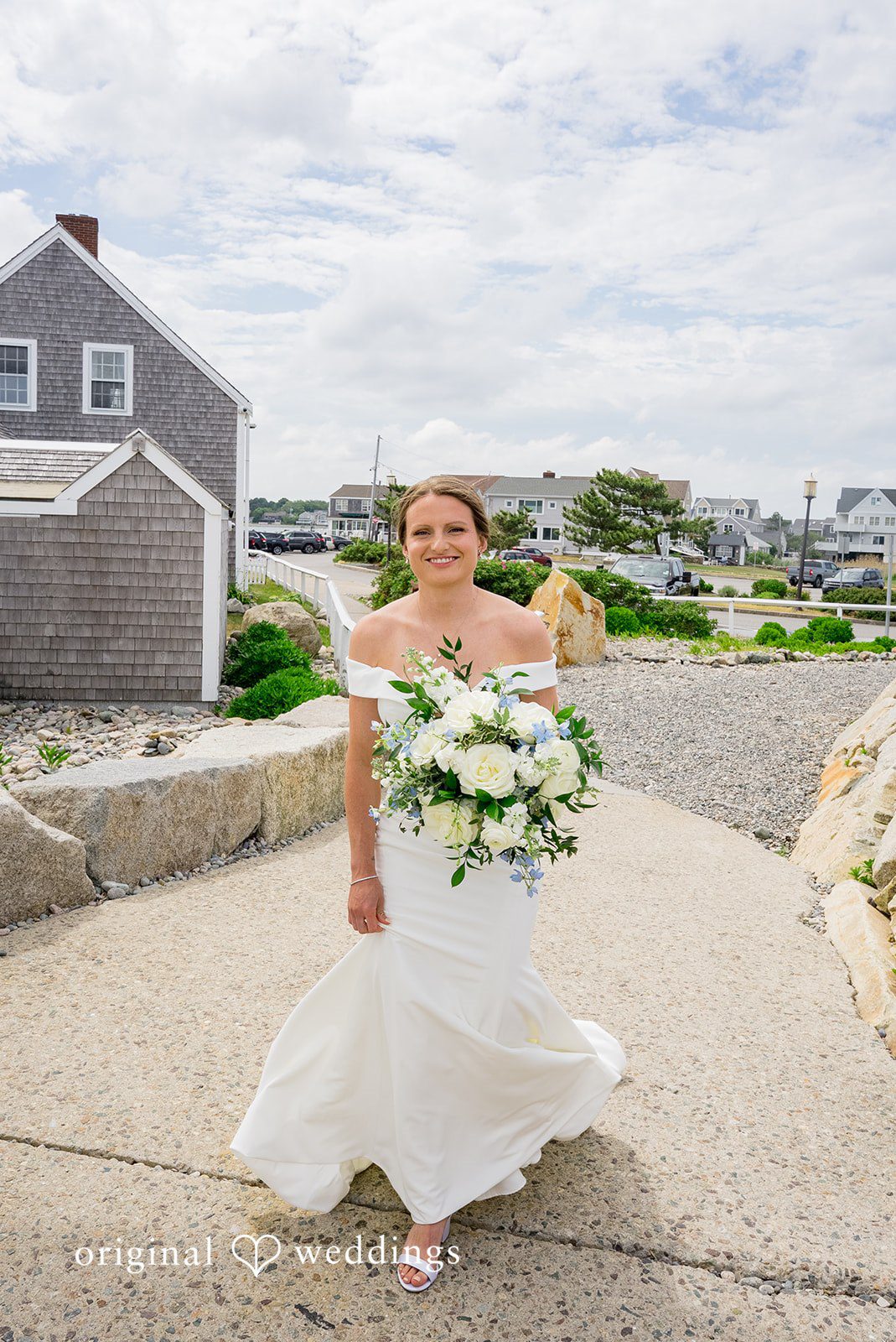 Molly + Joe A bride in a white gown smiles while holding a green and white floral bouquet.