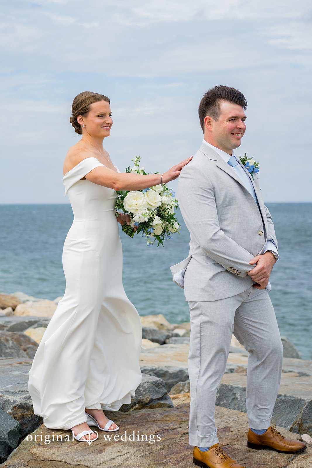 Molly + Joe A groom taps a bride on the shoulder for their first-look reveal near the coast.