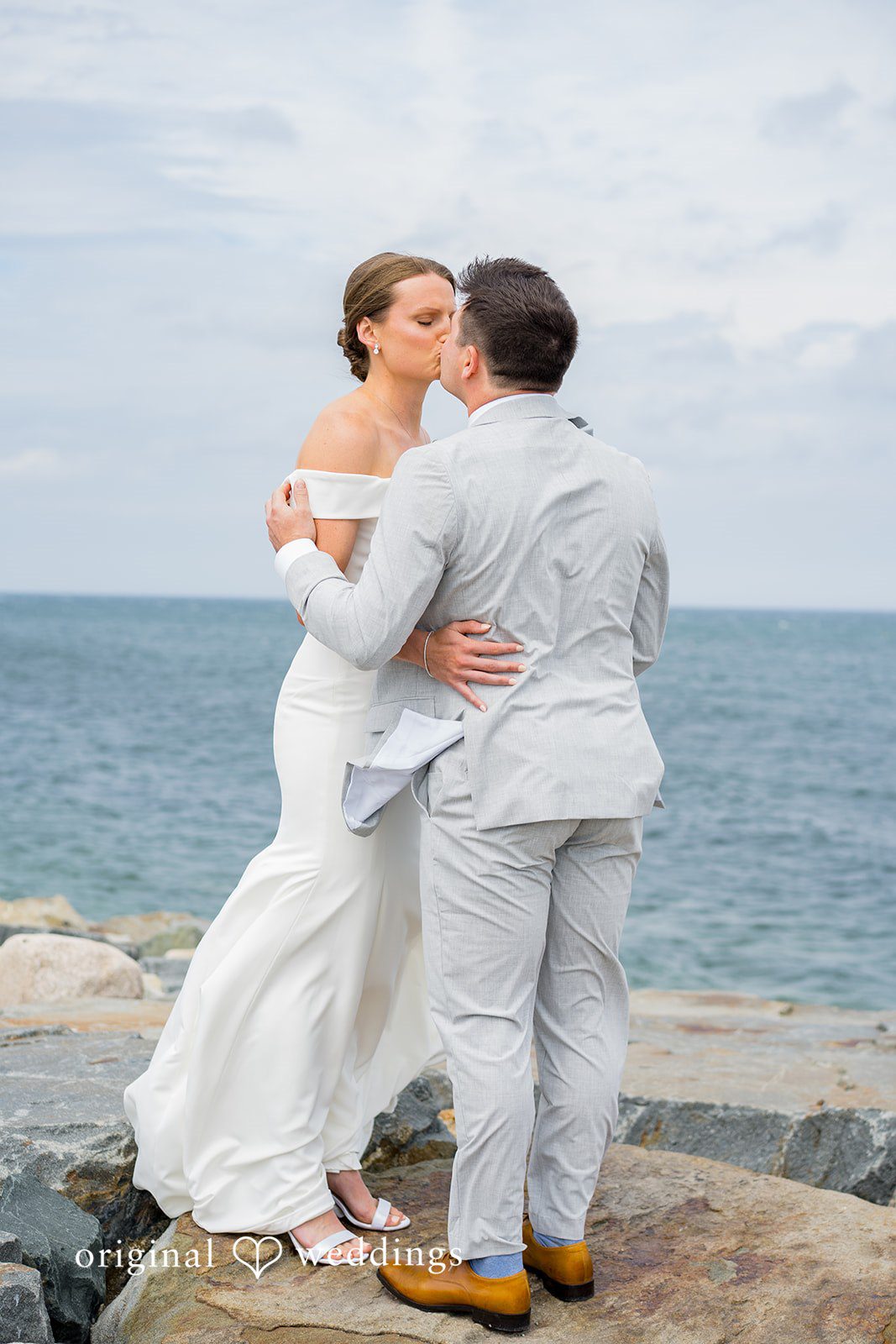 Molly + Joe A bride and groom embrace tightly while facing the ocean.