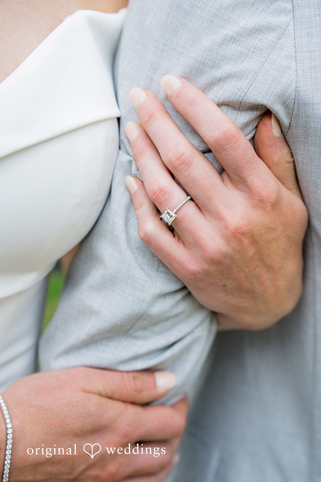 Molly + Joe A close-up view of a bride's hand showing off her wedding ring on the groom's shoulder.