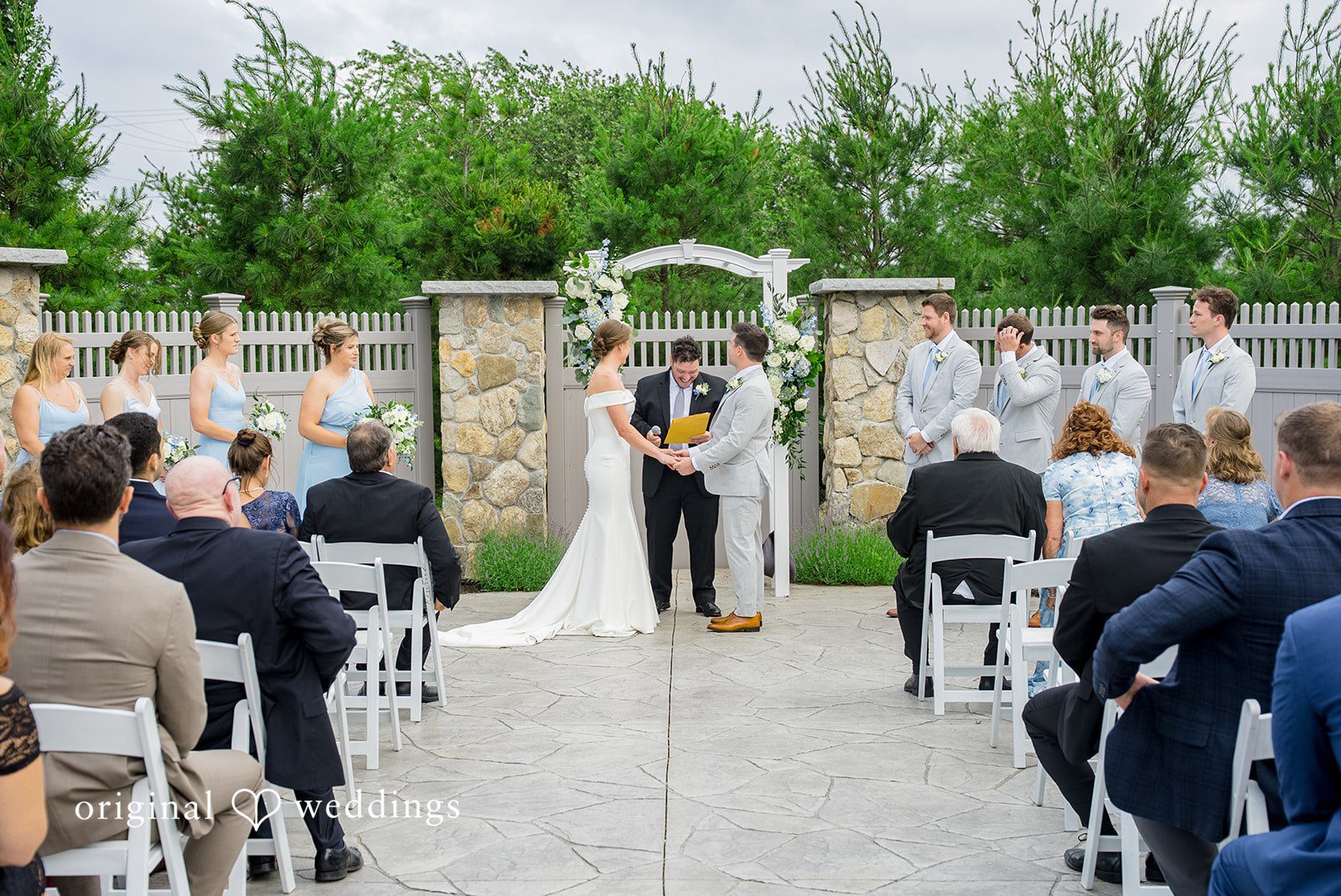 Molly + Joe Wedding guests sit in white chairs facing an altar during a wedding ceremony.