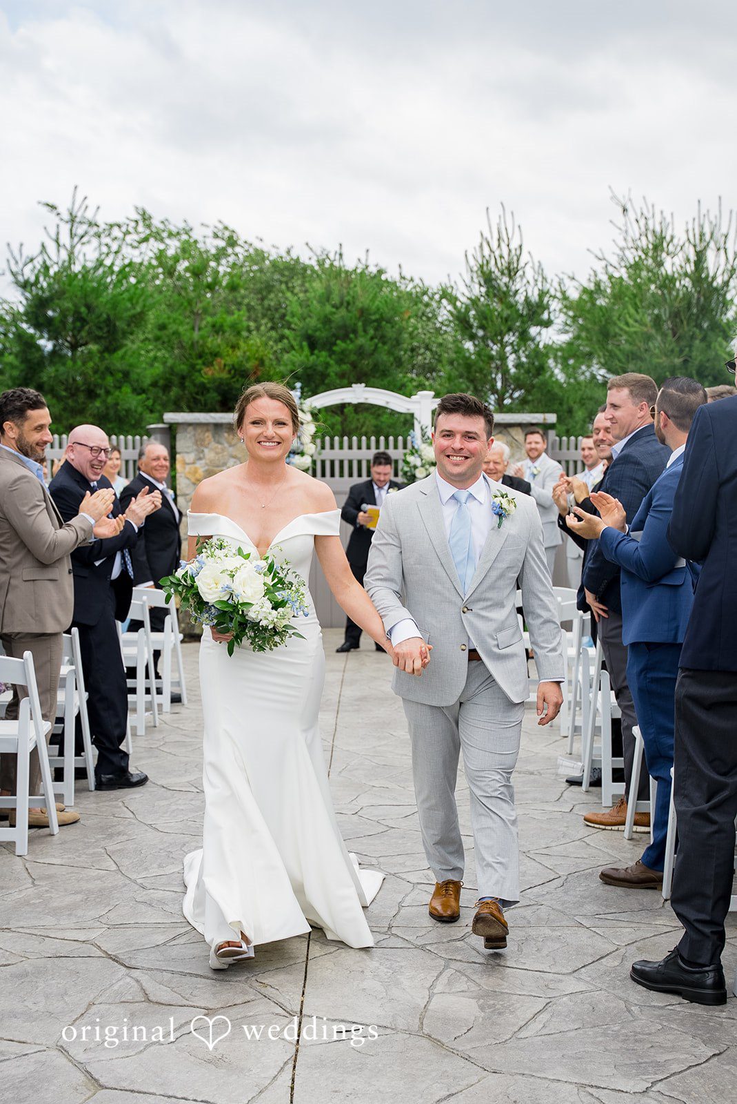 Molly + Joe A newly married couple walks down the aisle while guests applaud and cheer.