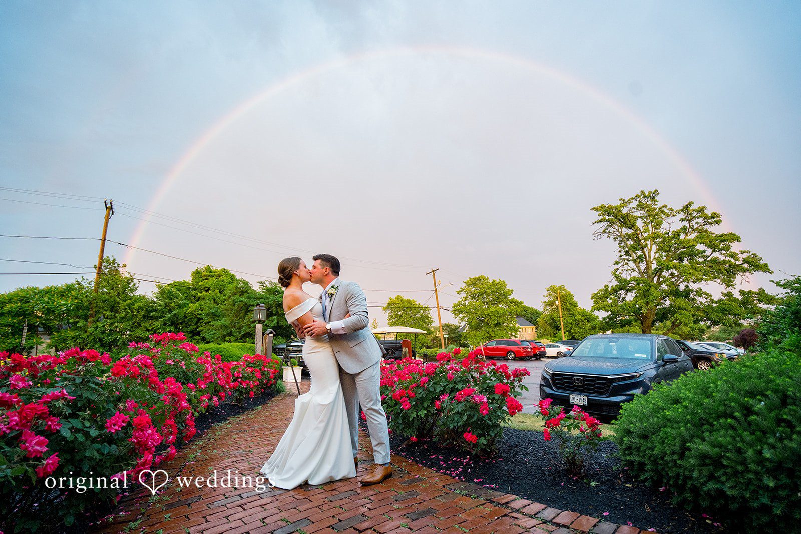 Molly + Joe A bride and groom share a kiss on a path near a golf course dome structure.